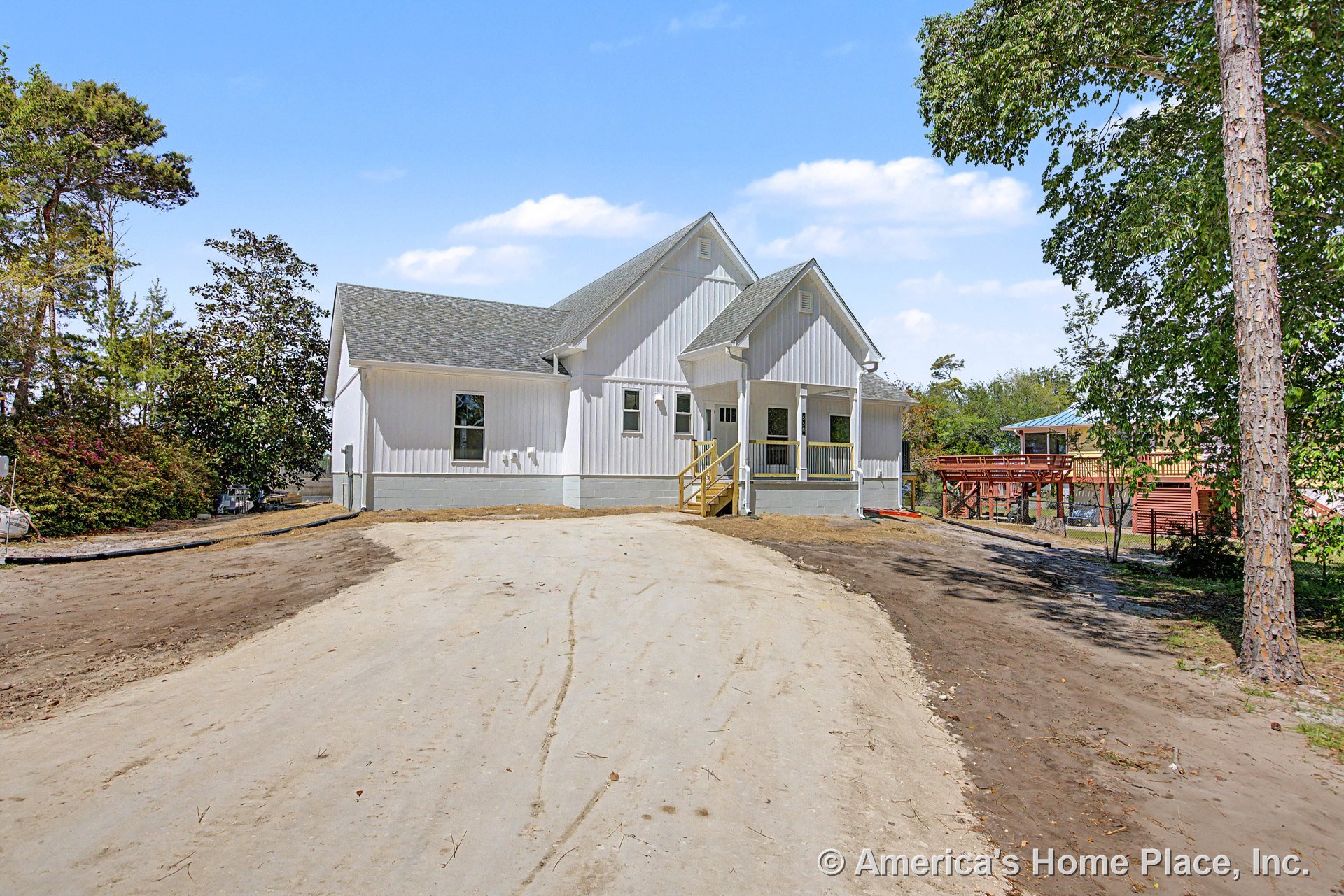 White vertical siding exterior with multiple gabled rooflines, gray shingle roof, covered front porch, wooden entry steps, white trim, porch railing, and several windows.