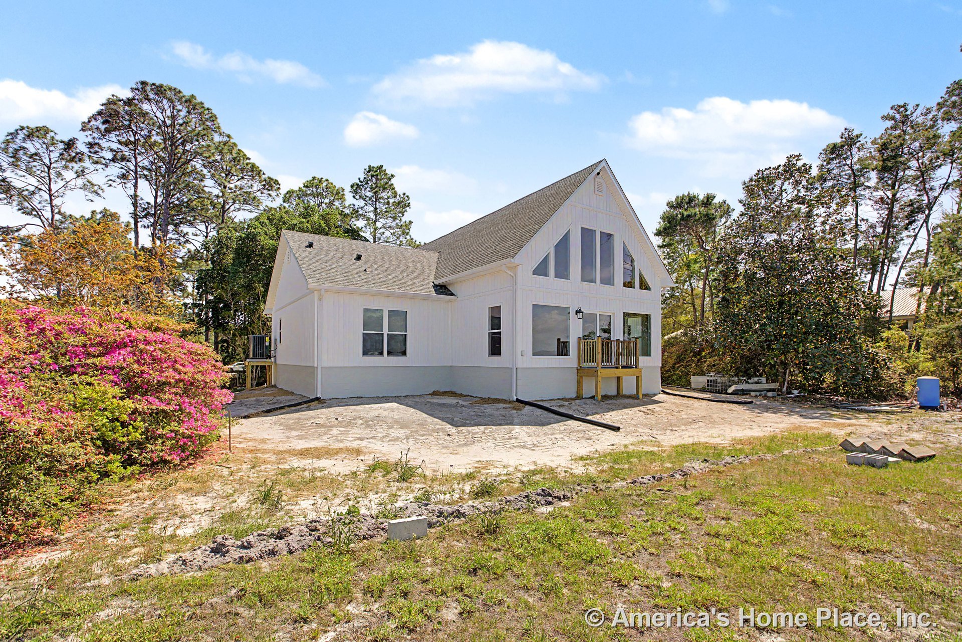 White vertical siding exterior with prominent triangular windows, small covered front porch, double-hung windows, gable roof, outdoor lighting fixture, and crisp trim detailing.
