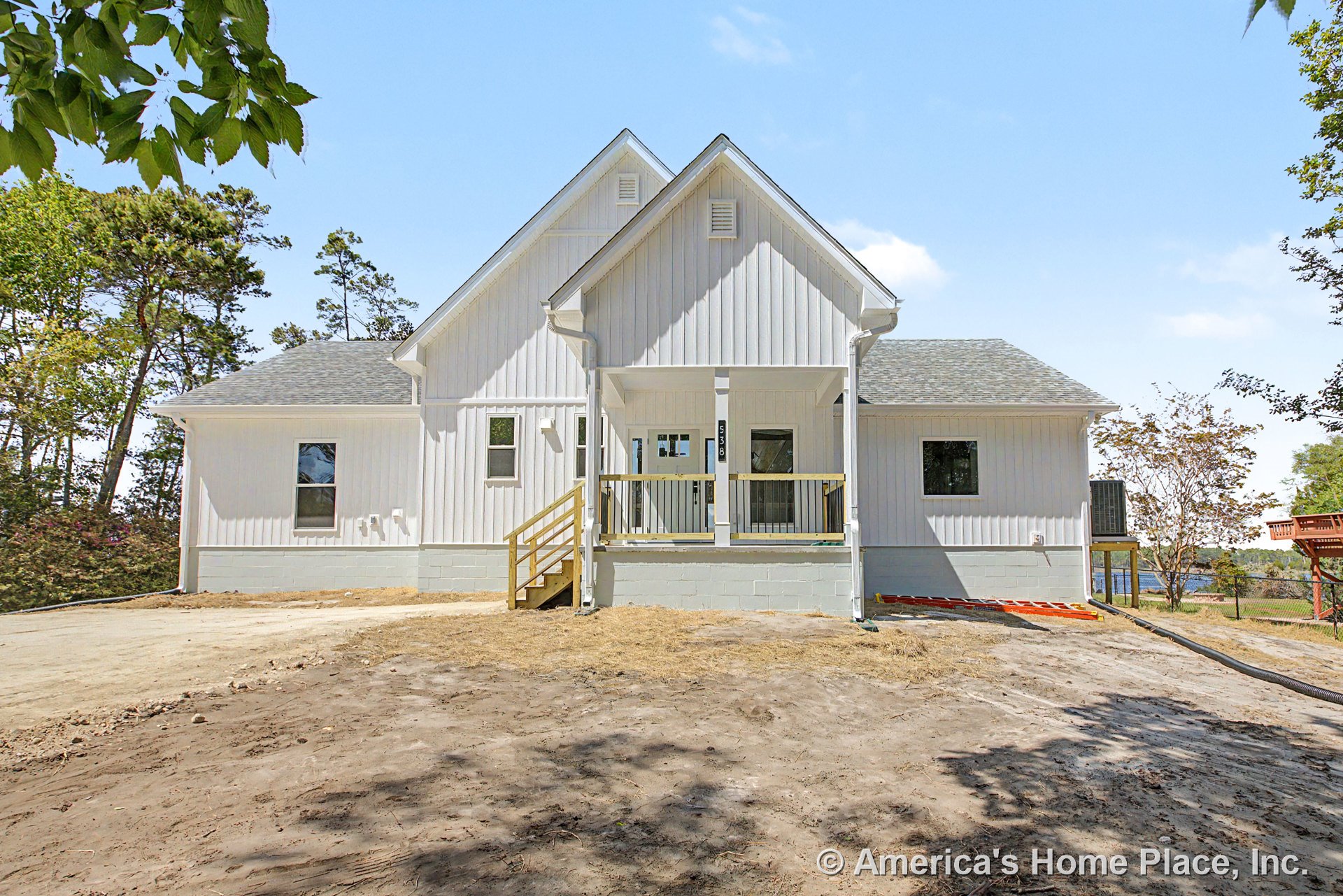 White vertical board and batten siding with gable roof, covered front porch supported by columns, concrete foundation, multiple rectangular windows, wooden porch steps, and