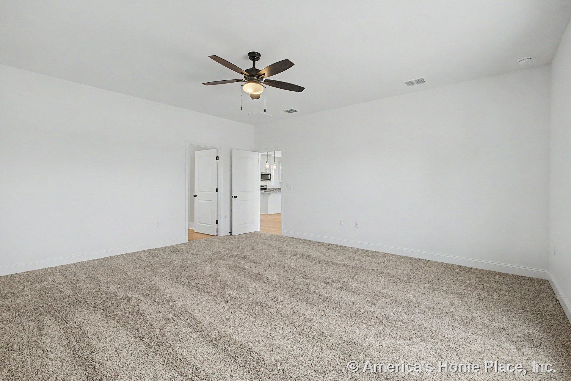 Neutral carpet flooring, white walls, ceiling fan with light, double white interior doors, white baseboards, recessed ceiling vent, open doorway, and trim detailing.