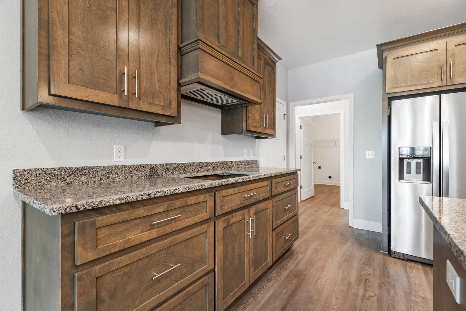 Kitchen featuring wood cabinets, marble countertops, stainless steel refrigerator, and modern appliances