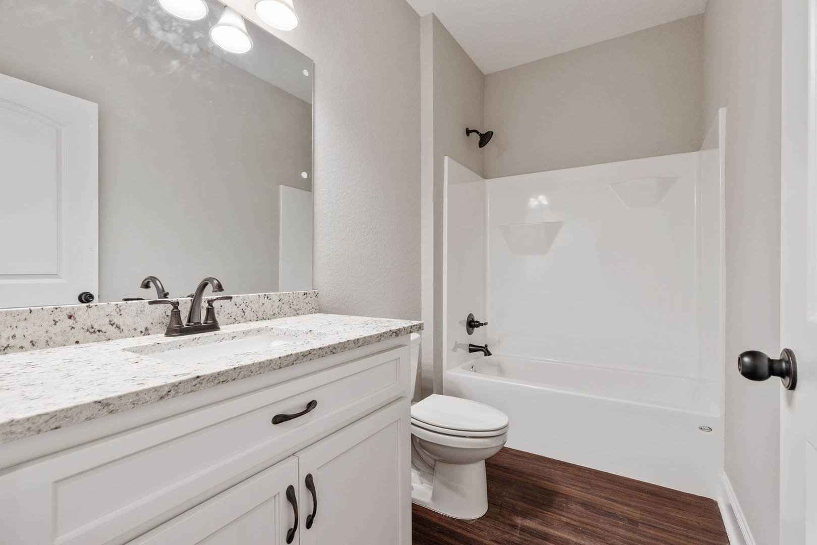 Modern bathroom featuring a white toilet with closed lid, white sink with chrome faucet, white walls accented by a black line, and a black door knob on a white door