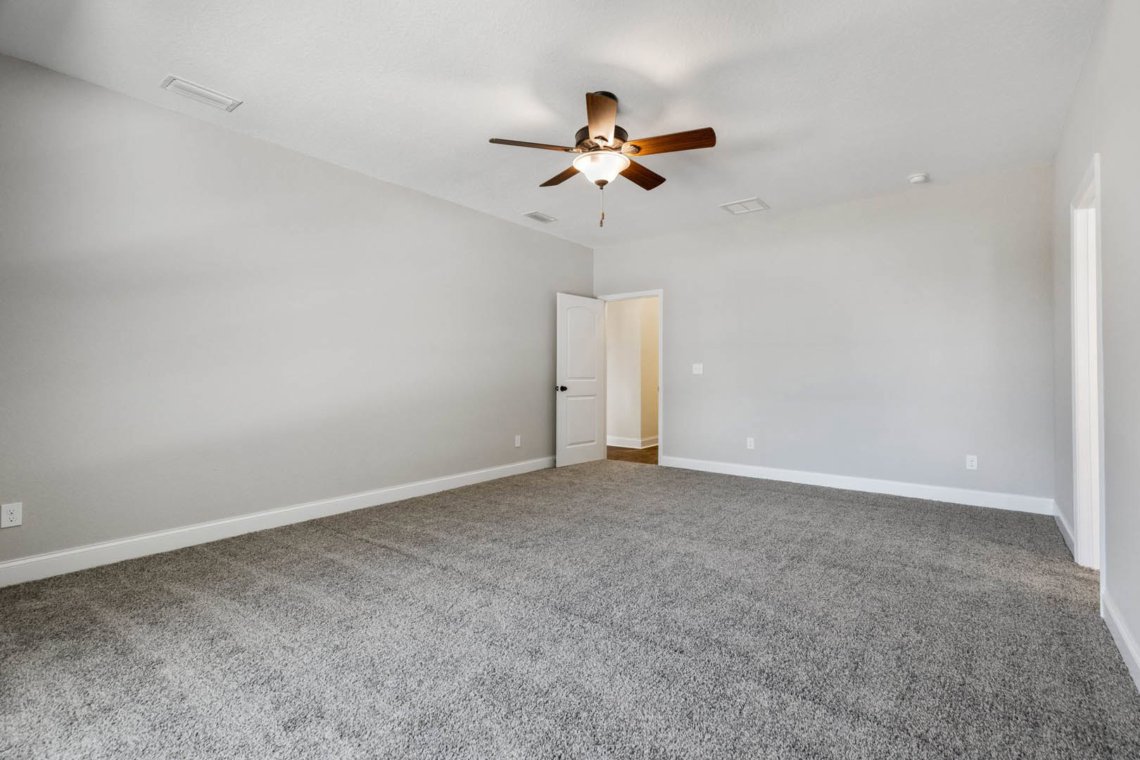 Carpeted room with white walls, yellow accent wall, ceiling fan with light fixture, and white door with black knob