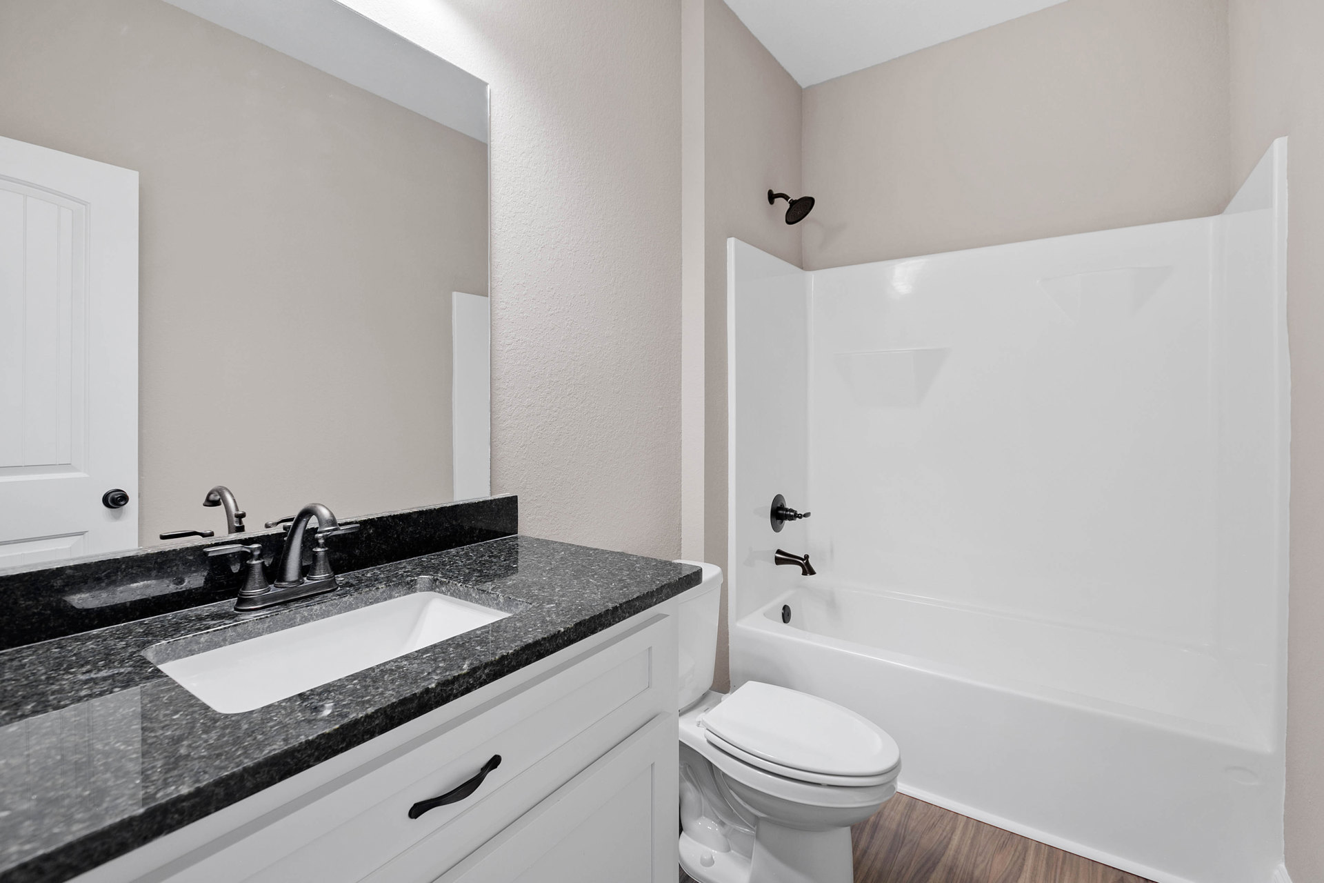 Modern bathroom featuring a white ceramic sink with chrome faucet, light wood vanity with drawers, glass-enclosed shower with tiled walls, and a white toilet adjacent to a white