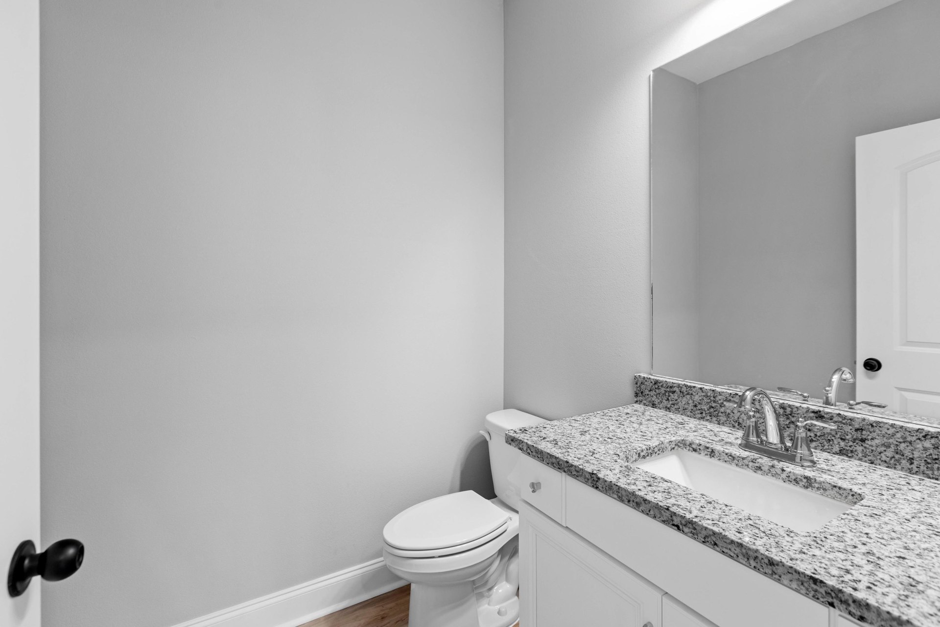 Marble countertop vanity with undermount sink, chrome faucet, frameless mirror, white toilet, and tiled walls in a modern bathroom