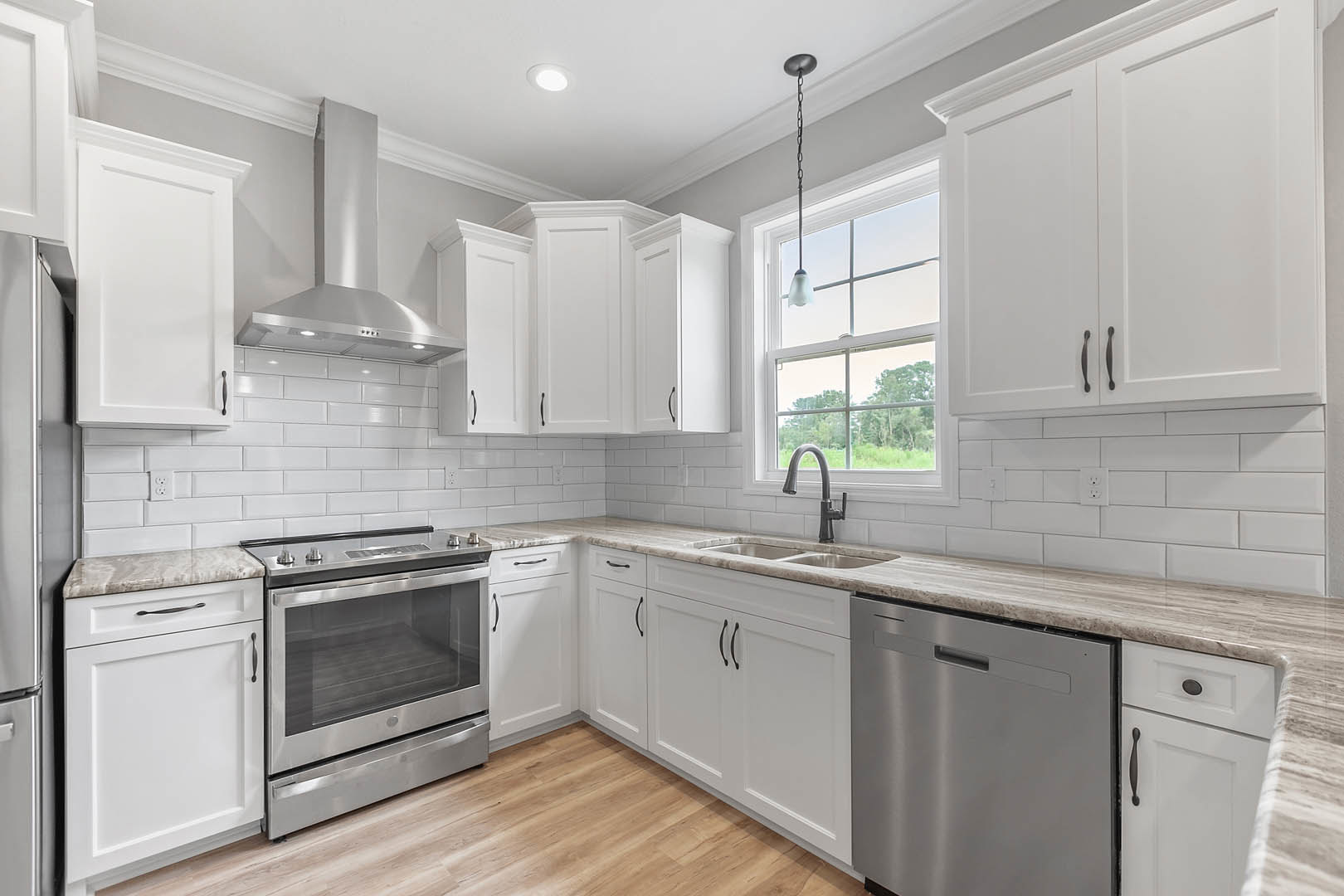 White kitchen with shaker cabinets, stainless steel stove and dishwasher, black hardware, light countertops, and gray tile backsplash.