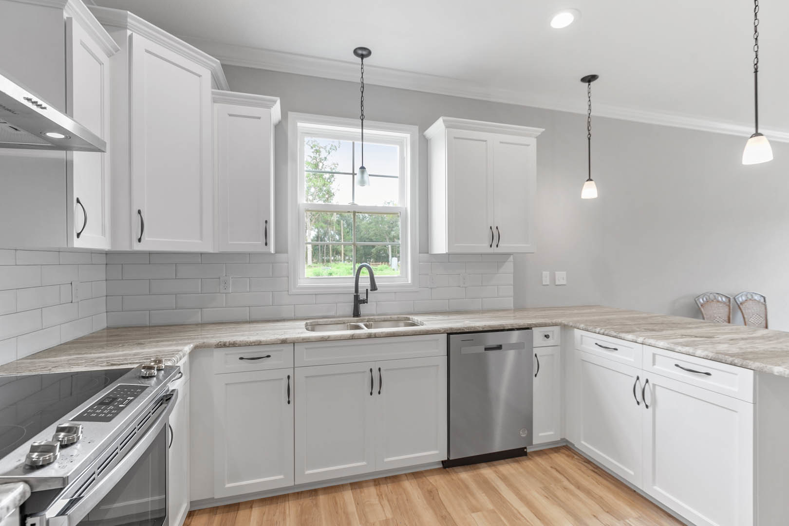 White shaker cabinets, stainless steel dishwasher, stone countertop, undermount sink, tile backsplash, ceiling light fixture, window with natural light