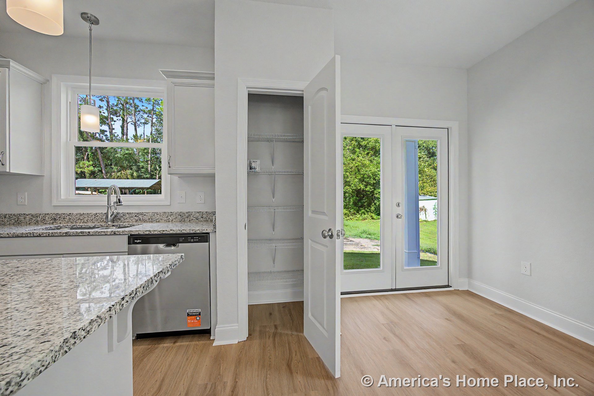 Granite countertops and white upper and lower cabinets in a kitchen with open pantry featuring wire shelving, stainless steel dishwasher, double glass patio doors, pendant