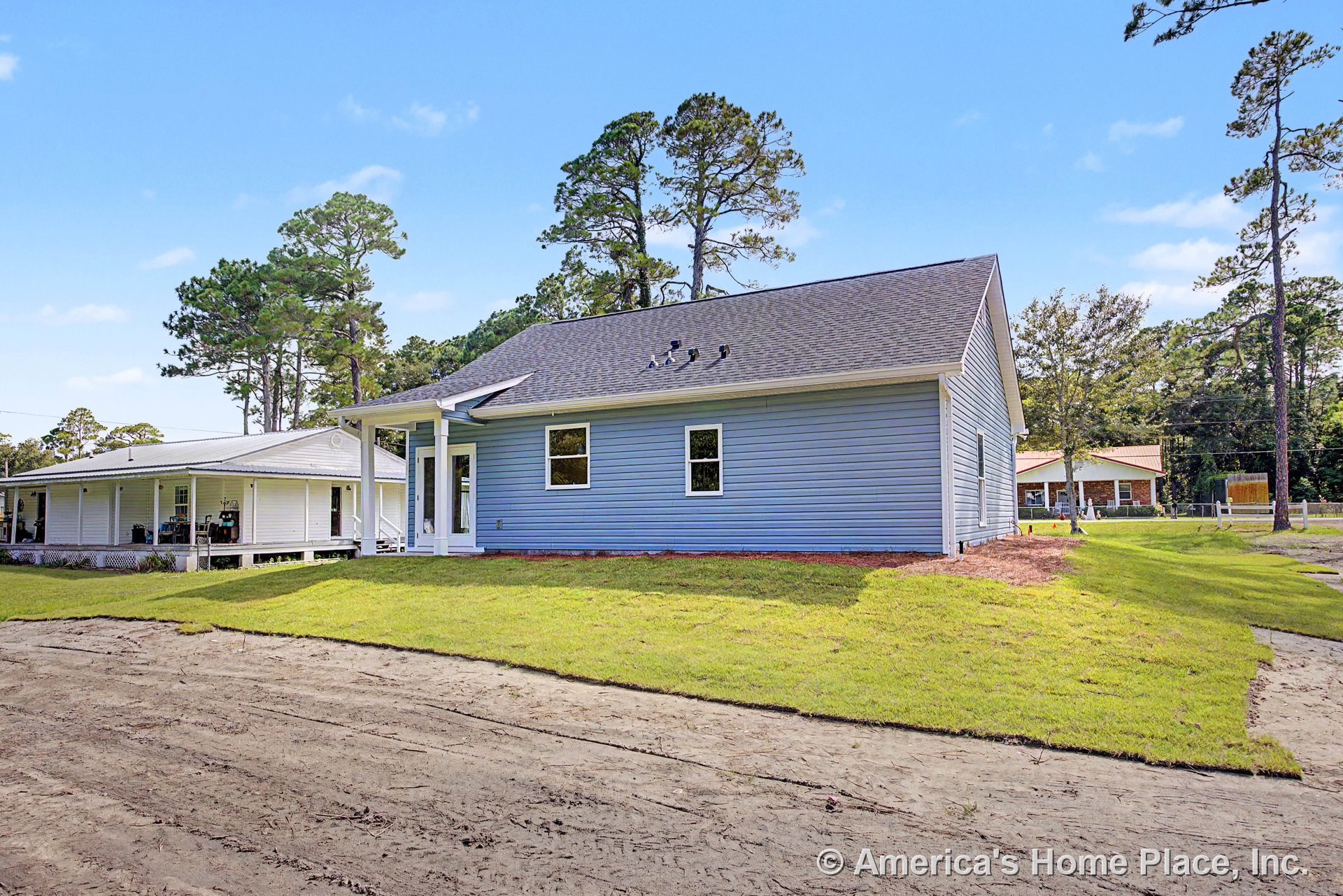 Blue vinyl siding exterior with white trim, gable roof featuring roof vents, covered entry porch, double-hung windows, entry door, and freshly laid lawn in front of new one-story
