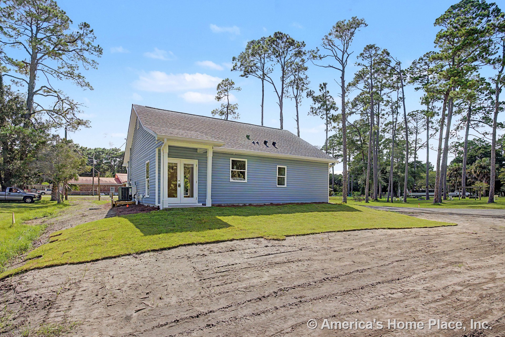 Blue vinyl siding exterior with gable roof, covered rear entry featuring double glass doors, white trim accents, and a single window.