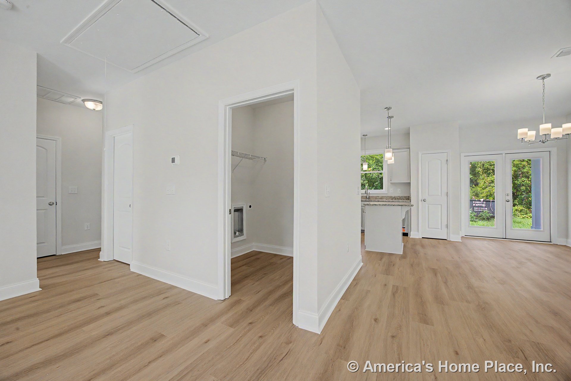 Open floor plan with light wood plank flooring, granite kitchen countertops, pendant and chandelier lighting, double glass patio doors, recessed ceiling, laundry closet with wire