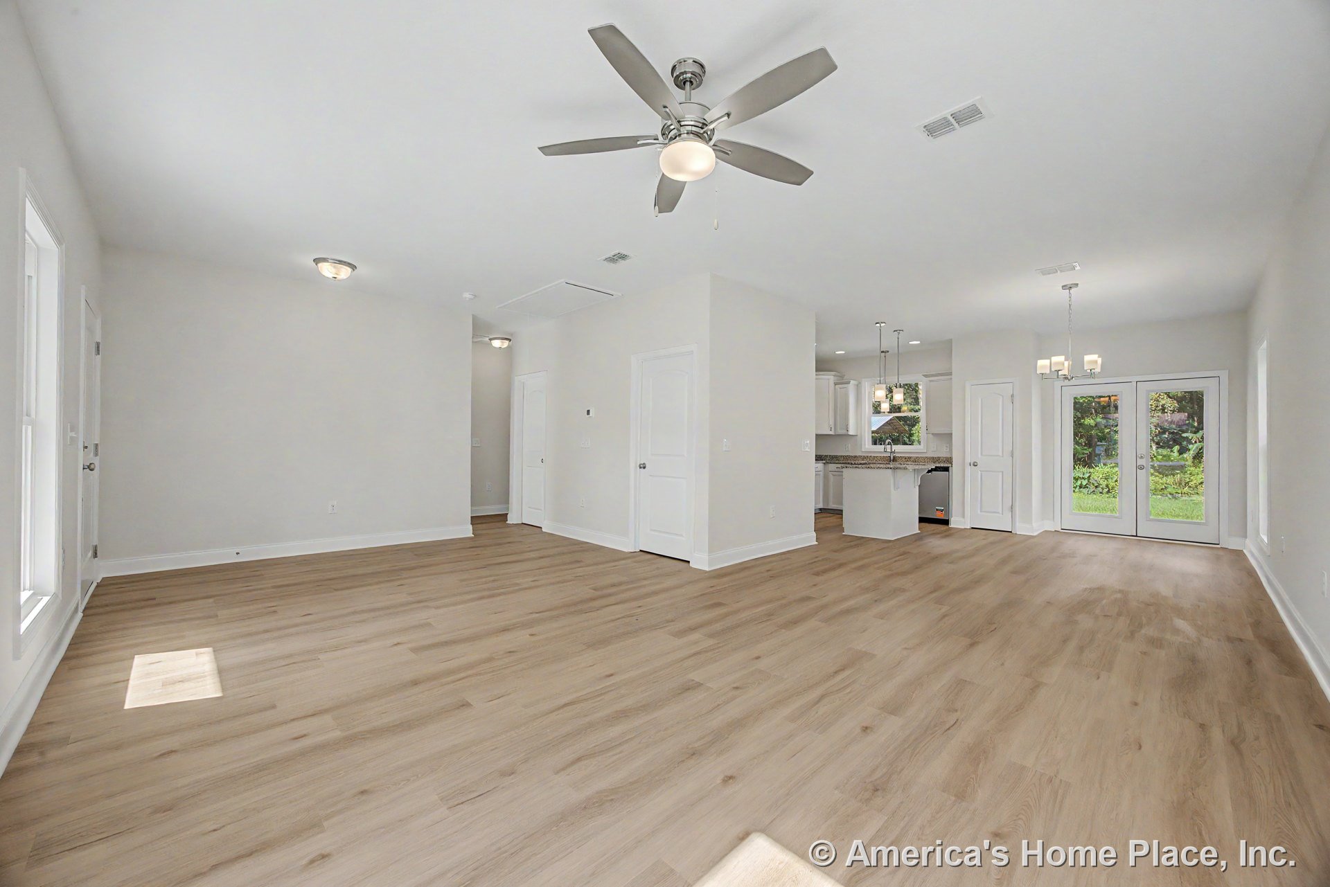 Open concept living area with light wood plank flooring, white trim and baseboards, ceiling fan with integrated light, recessed and pendant lighting, double glass patio doors, and