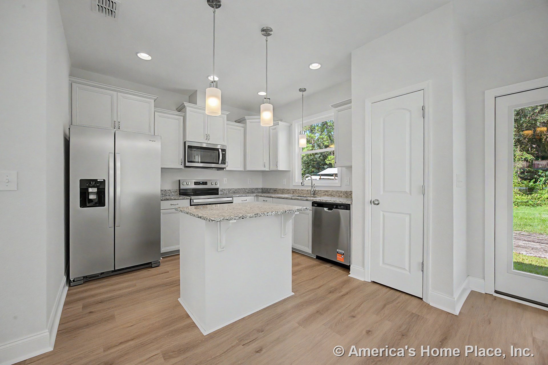White shaker cabinets with granite island countertop, stainless steel refrigerator, dishwasher, and microwave, pendant lighting fixtures above island, wood-look flooring, large