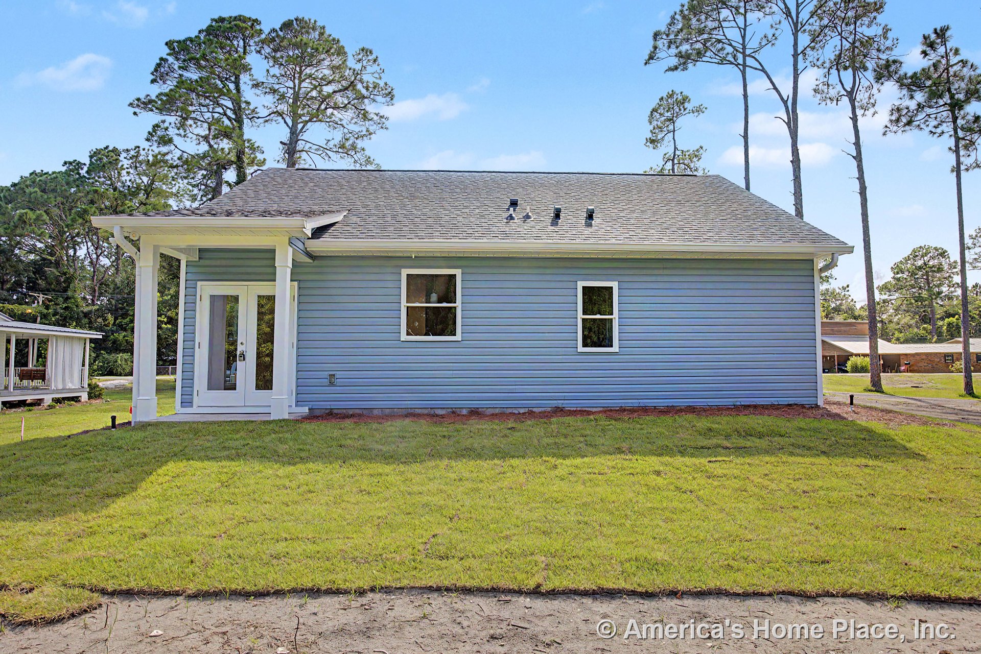 Blue vinyl siding exterior with white trim, covered entry porch supported by columns, double glass exterior doors, two rectangular windows, and gray shingle roof.