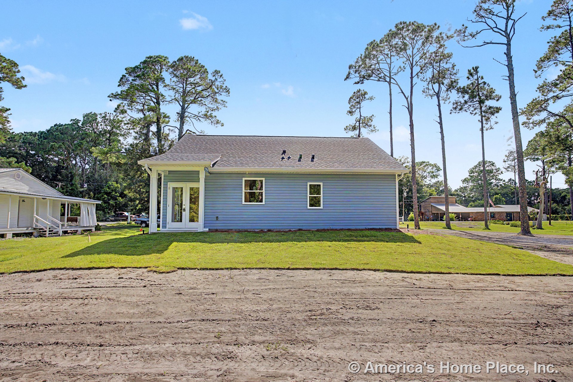 Blue horizontal siding exterior with gable roof, covered rear porch featuring double glass doors, two rectangular windows, white trim and columns, roof vents, and landscaped yard.