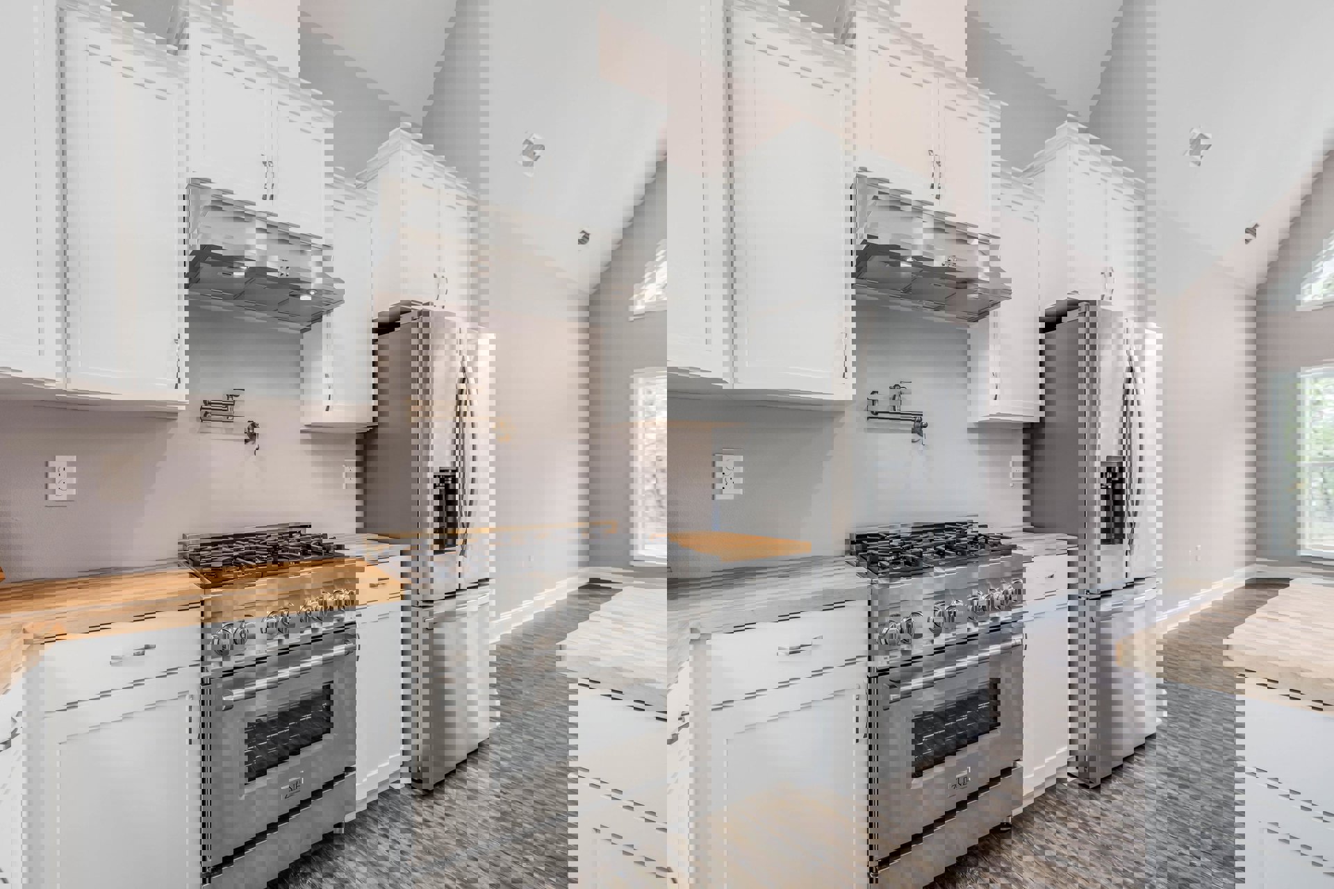 White kitchen cabinets, stainless steel refrigerator and stove, light countertops, white door with matching trim, square wall vent, and white electrical outlet.