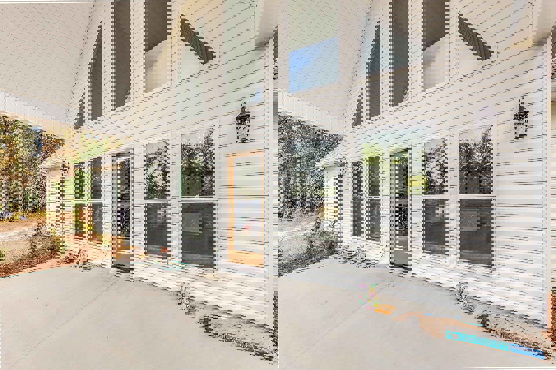 White siding house with covered porch, glass-paneled front door, screened windows, and outdoor wall light fixture