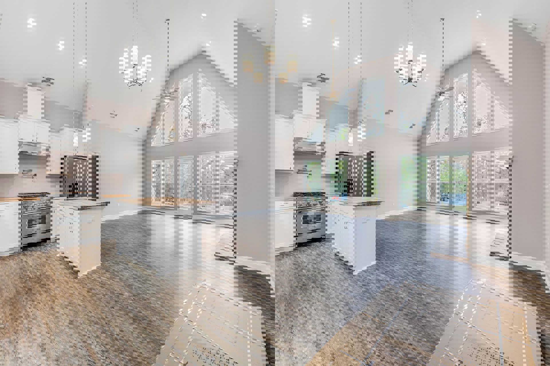 Spacious kitchen with high ceiling, white island featuring wood countertop, stainless steel refrigerator with water dispenser, stove beneath a window, white door with glass panel