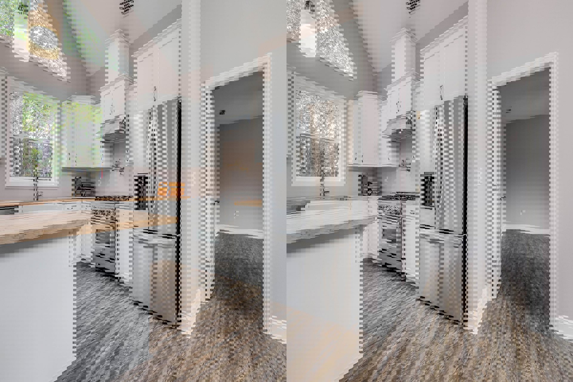 Kitchen with stainless steel refrigerator, stove, and dishwasher, wood flooring, white cabinetry, stone countertops, large window above sink with tree view, modern pendant light