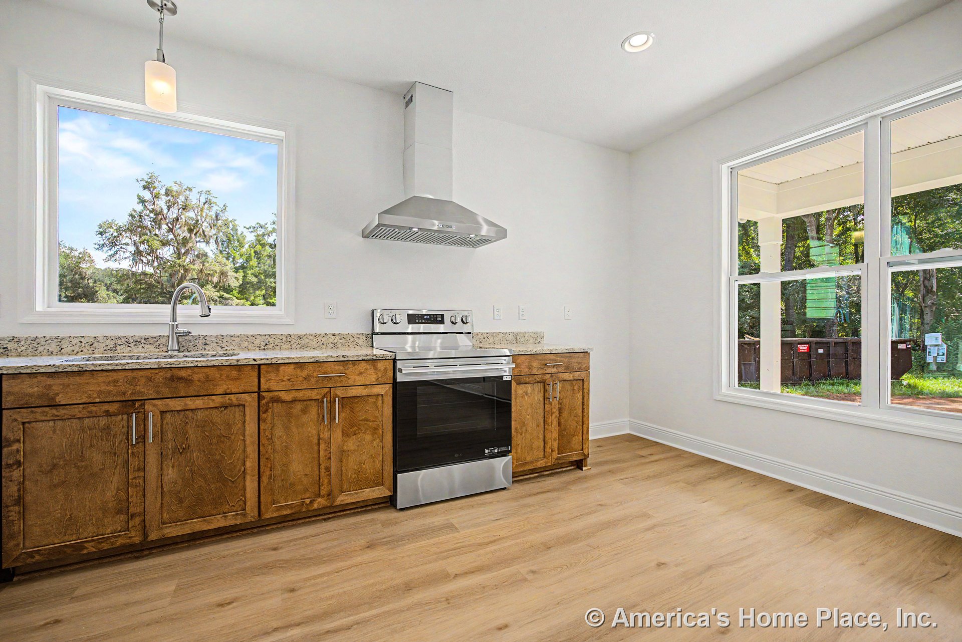 Wood shaker cabinets and granite countertops with stainless steel range and hood, large picture windows, pendant and recessed lighting, light wood flooring, and open kitchen