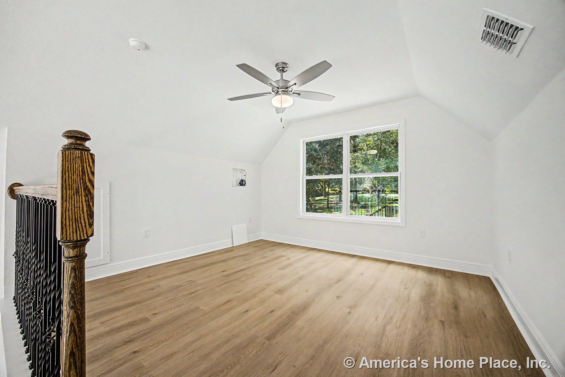 Upstairs bonus room with light wood plank flooring, white walls and trim, vaulted ceiling, ceiling fan with light fixture, large double window providing natural light, and wood and