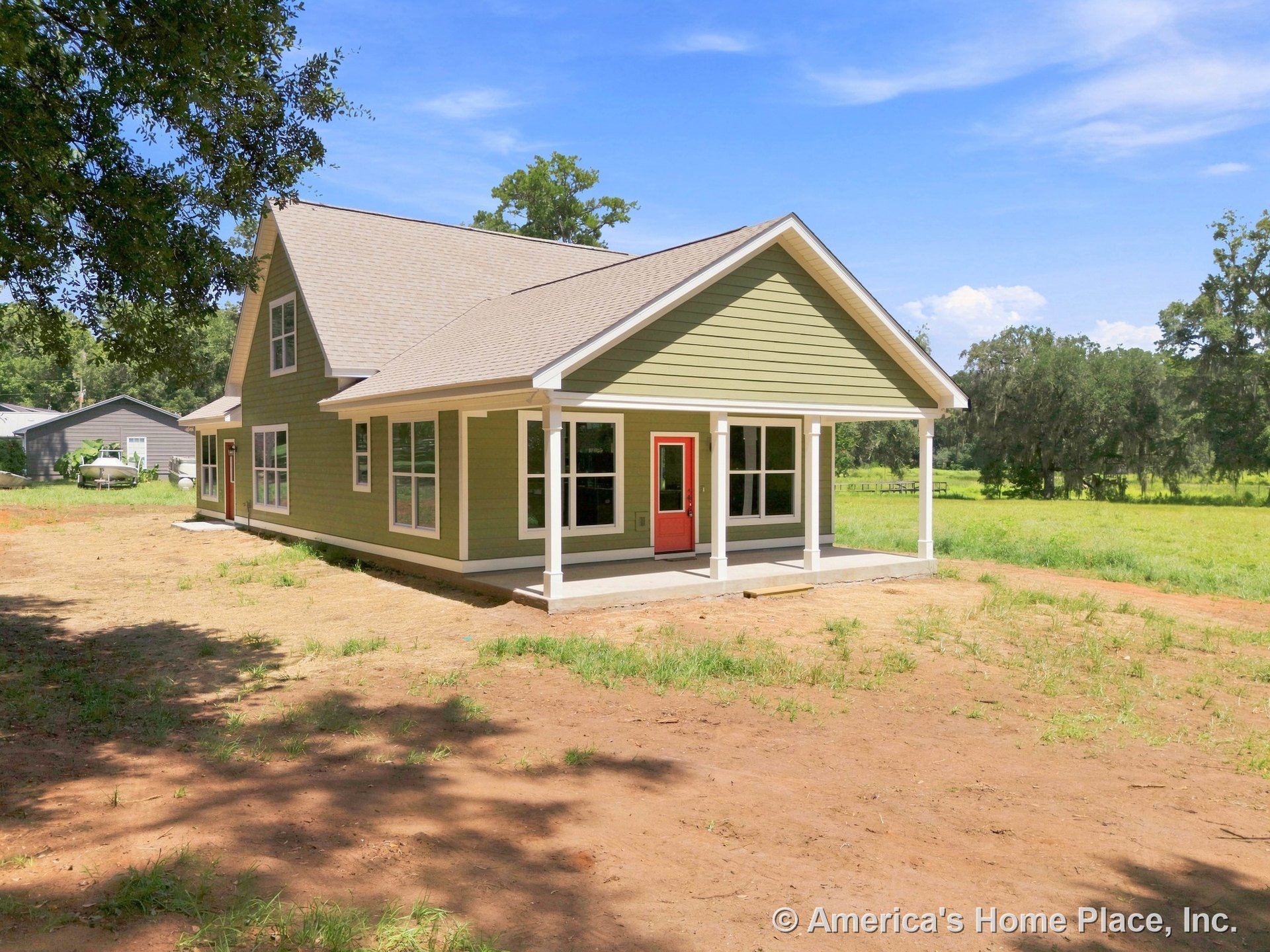 Covered front porch with white columns, red front door, green horizontal siding, gable shingle roof, and multiple large rectangular windows.