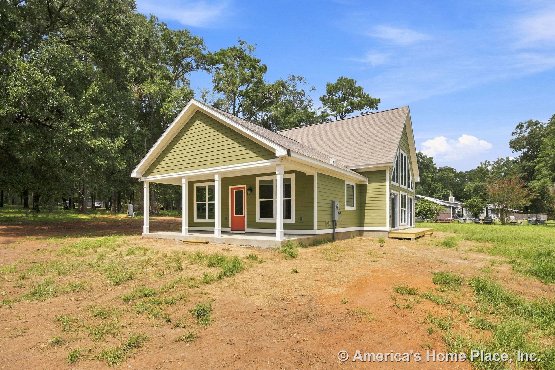 Green horizontal lap siding with white trim and columns, covered front porch, red front door, large gable windows, and steep roof pitch.