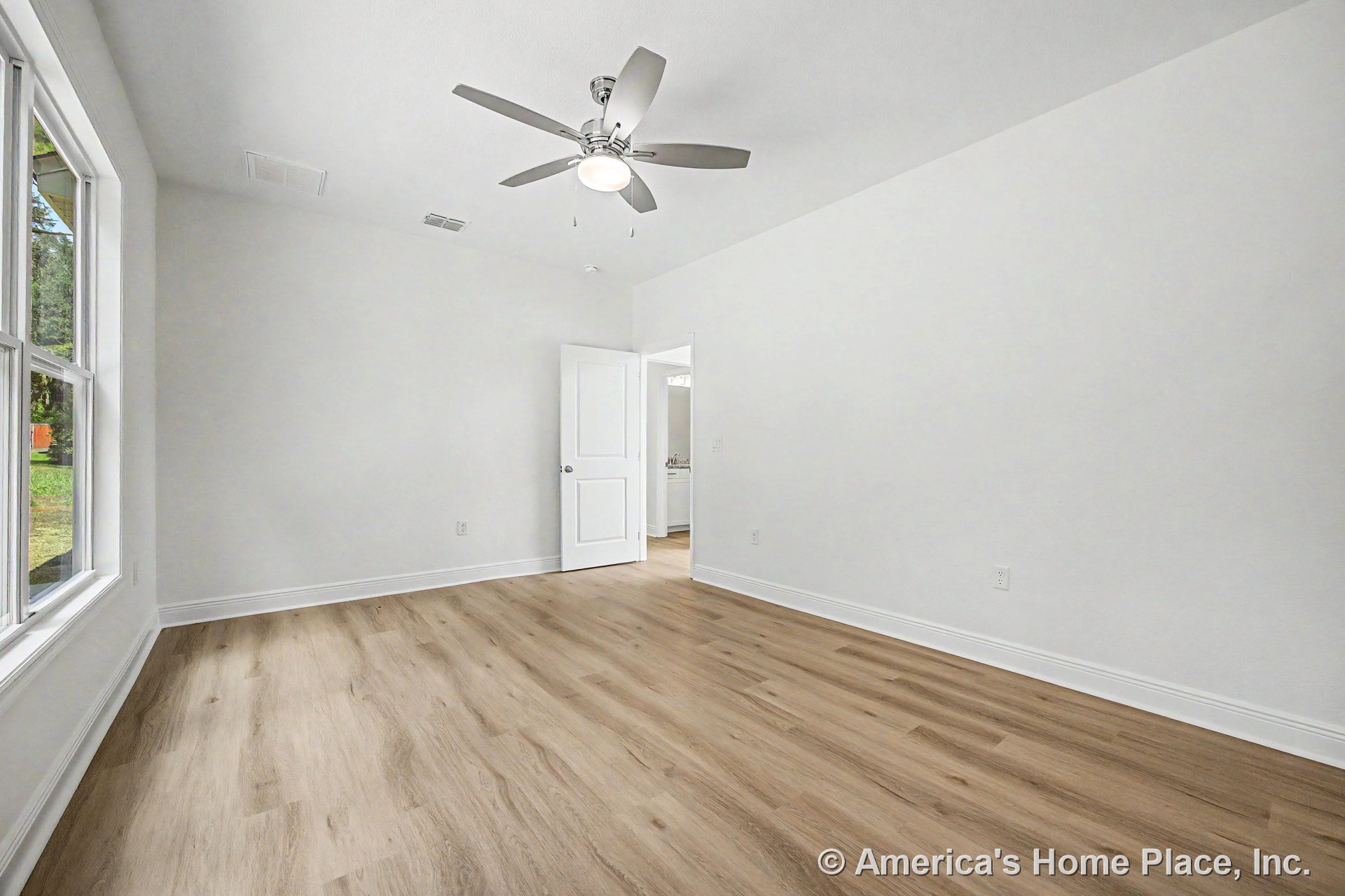 Bedroom with light wood plank flooring, white walls and baseboards, large window with white trim, ceiling fan featuring built-in lighting, smooth white ceiling, and white paneled