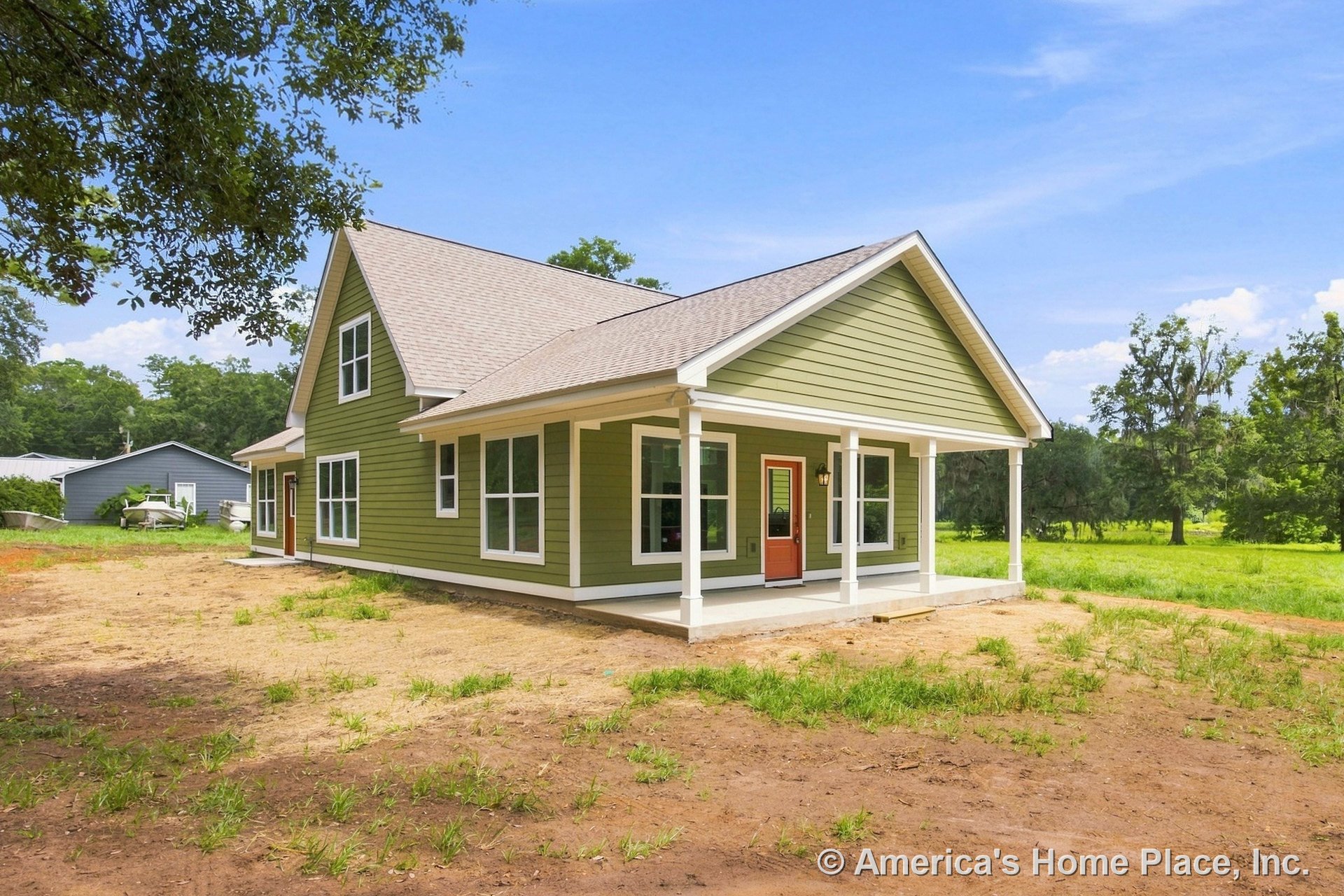 Covered front porch with white columns, green horizontal siding, large windows, gable roof, and a contrasting red front door with white trim accents.