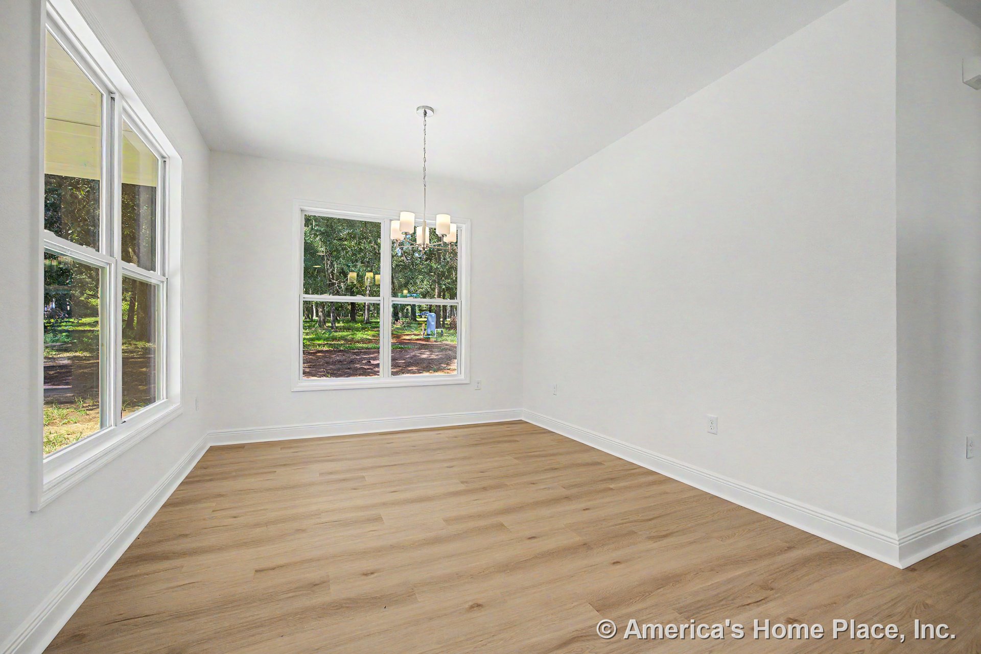 Dining room with large double windows, light wood plank flooring, white painted trim, modern chandelier, smooth white walls, rectangular layout, and neutral palette.