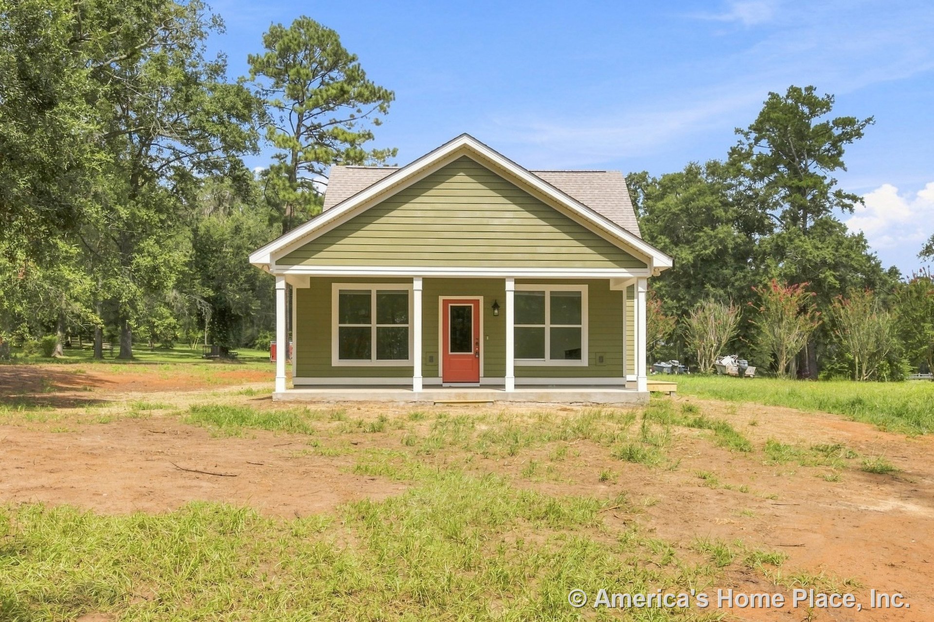 Covered front porch with white columns and trim, green horizontal siding, red front door, double window units, gable roof, and concrete porch floor on a single-story home.