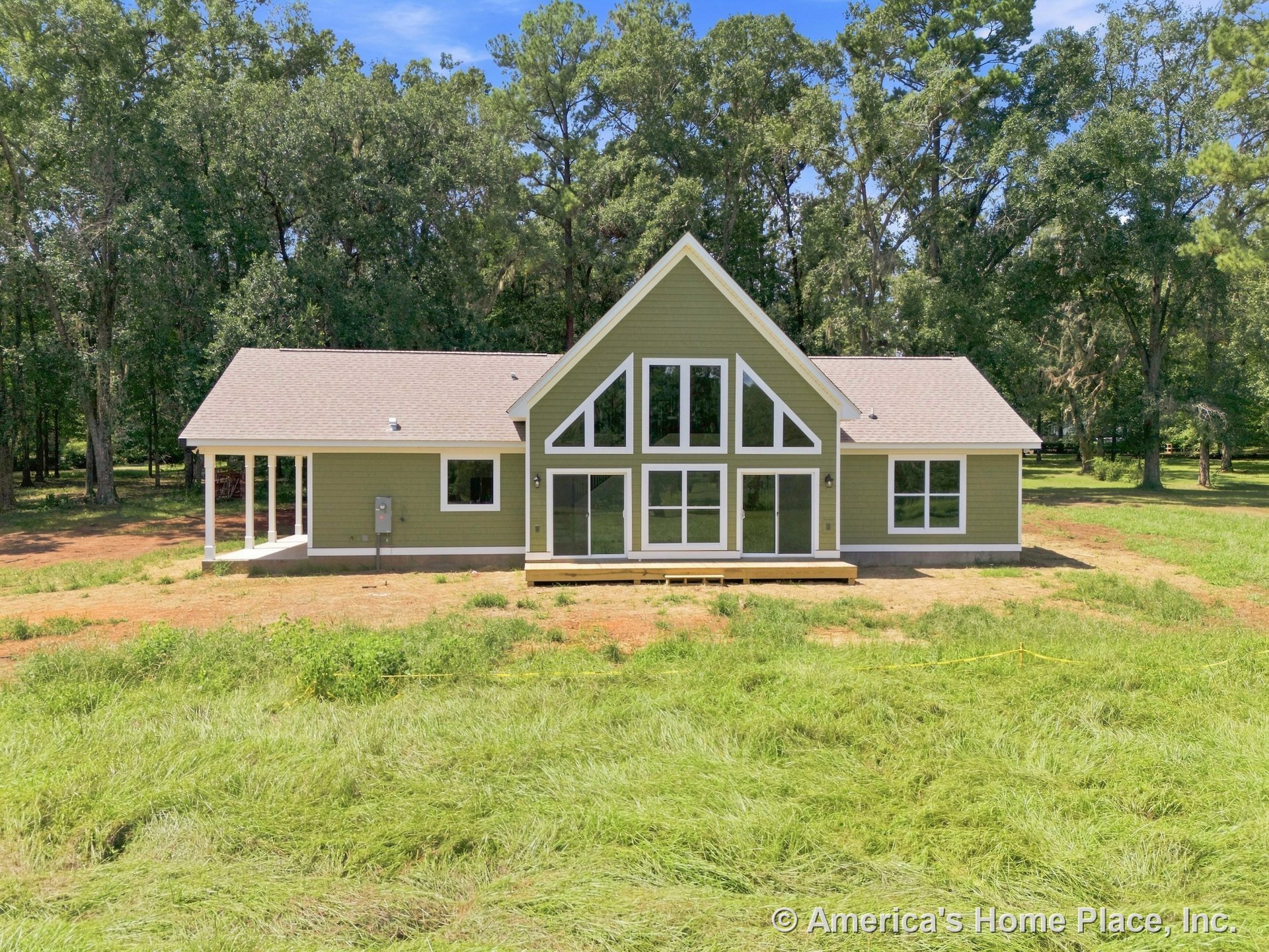 Symmetrical gable roof with prominent triangular window array, covered porch entry supported by columns, horizontal lap siding, multiple sliding glass doors, contrasting trim, and