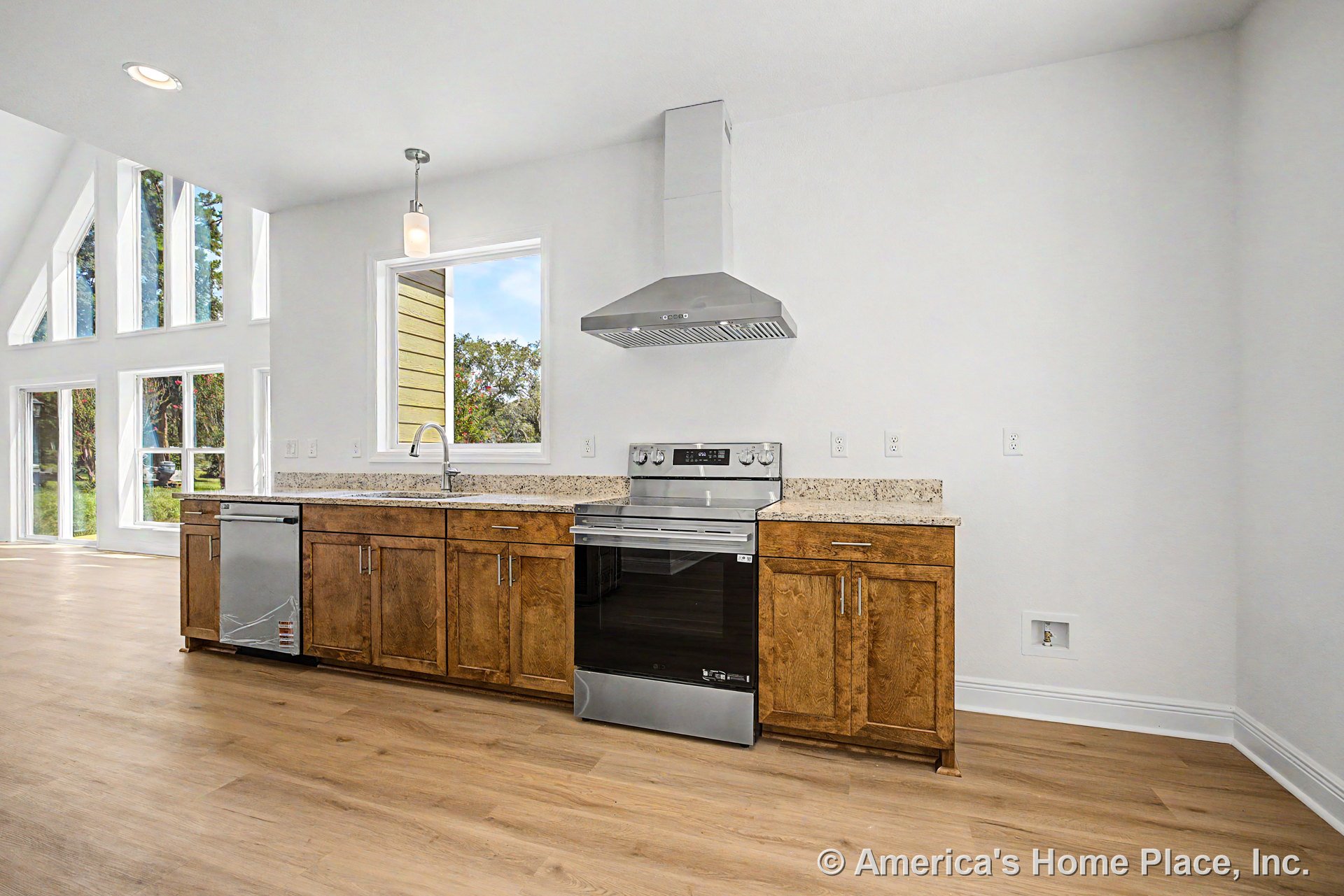 Wood cabinetry kitchen with granite countertops, stainless steel range and hood, built-in dishwasher, large window wall, pendant lighting, light wood flooring, and open floor plan