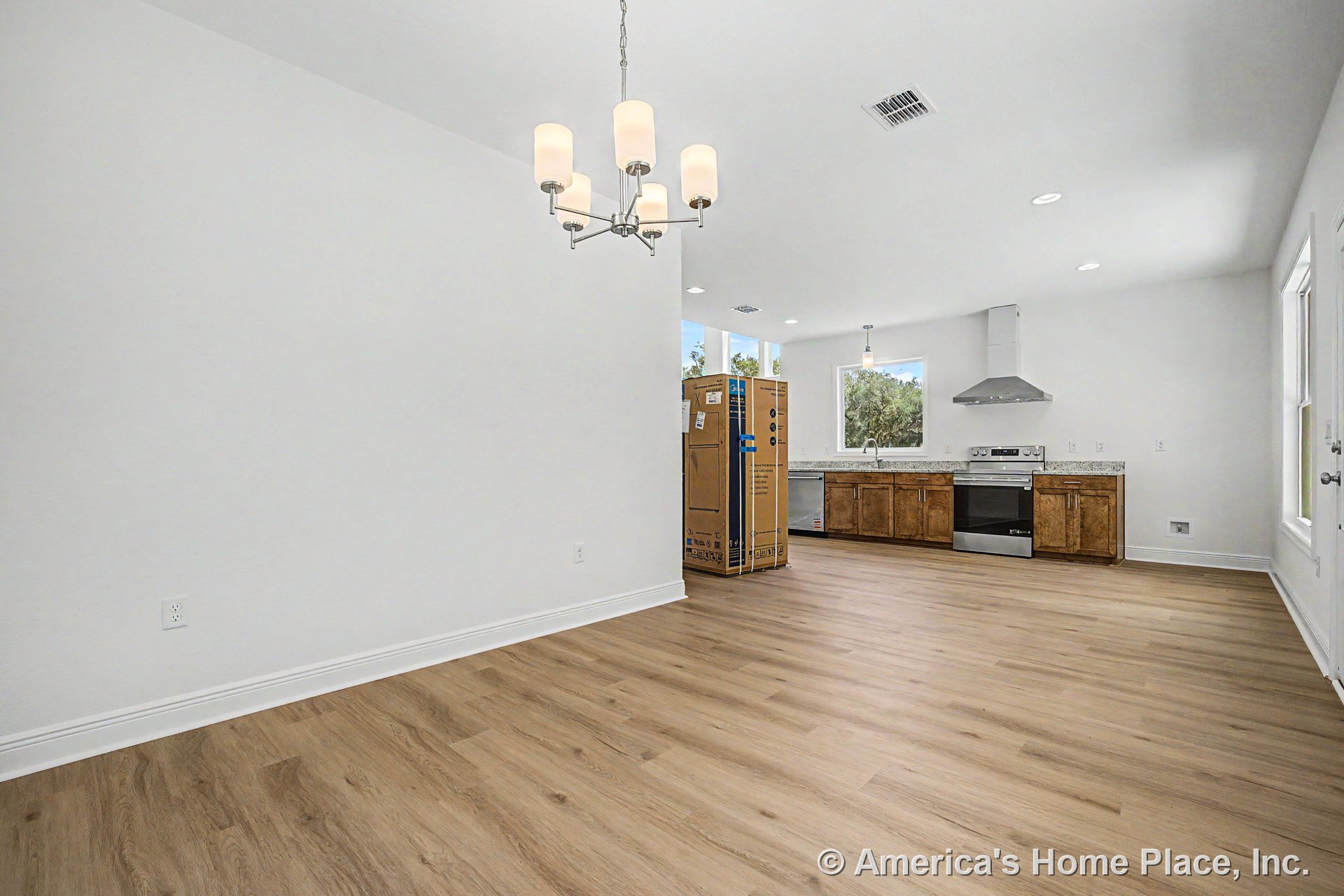 Open kitchen and dining area with wood-look plank flooring, granite countertops, stainless steel range and hood, natural wood cabinetry, pendant and recessed ceiling lights, large