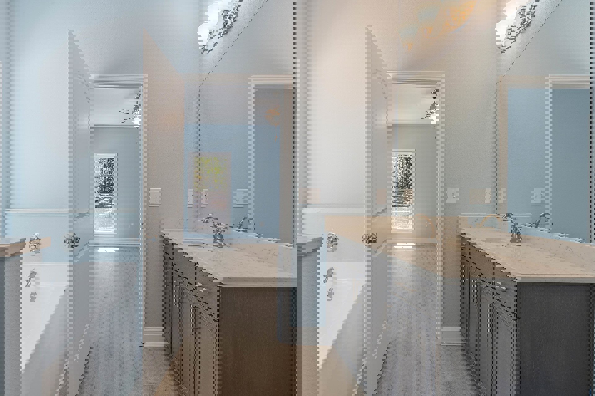 Bathroom with white paneled door, rectangular sink on stone countertop, chrome faucet, tiled walls, window overlooking trees and playground, close-up of brushed metal door knob