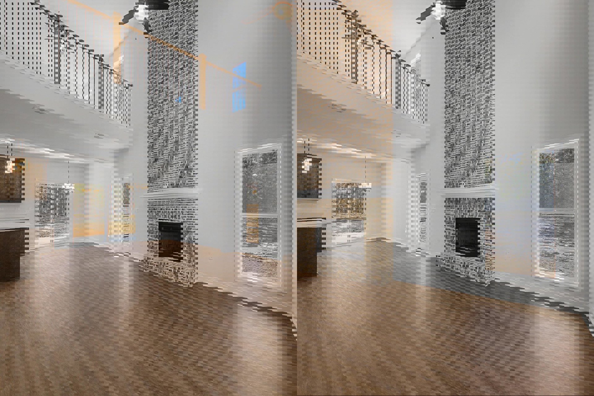 Living room with hardwood floors, brick fireplace, white-framed window, ceiling light fixture, and neutral walls