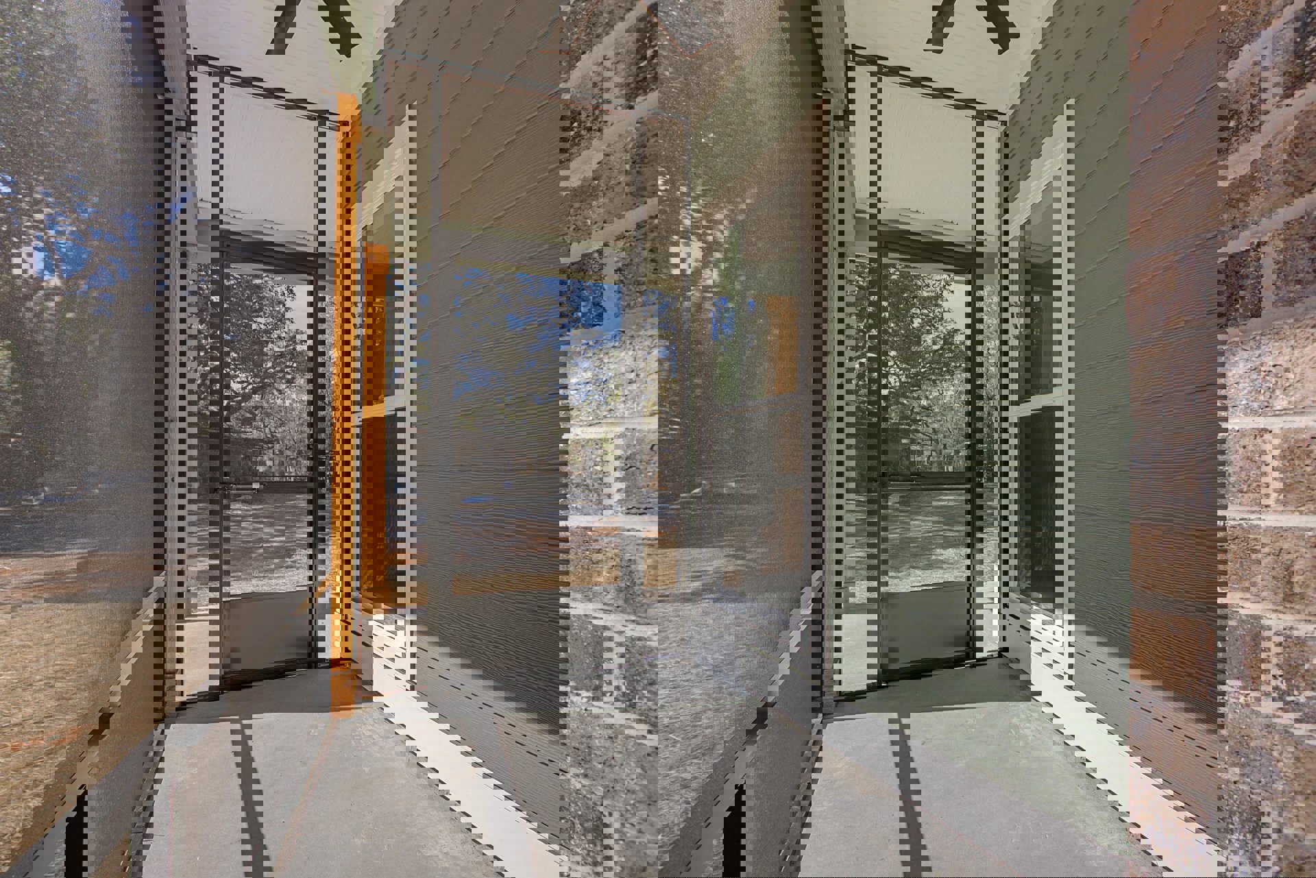 Covered porch with brick wall, green siding with white trim, glass door, ceiling fan, and screened door