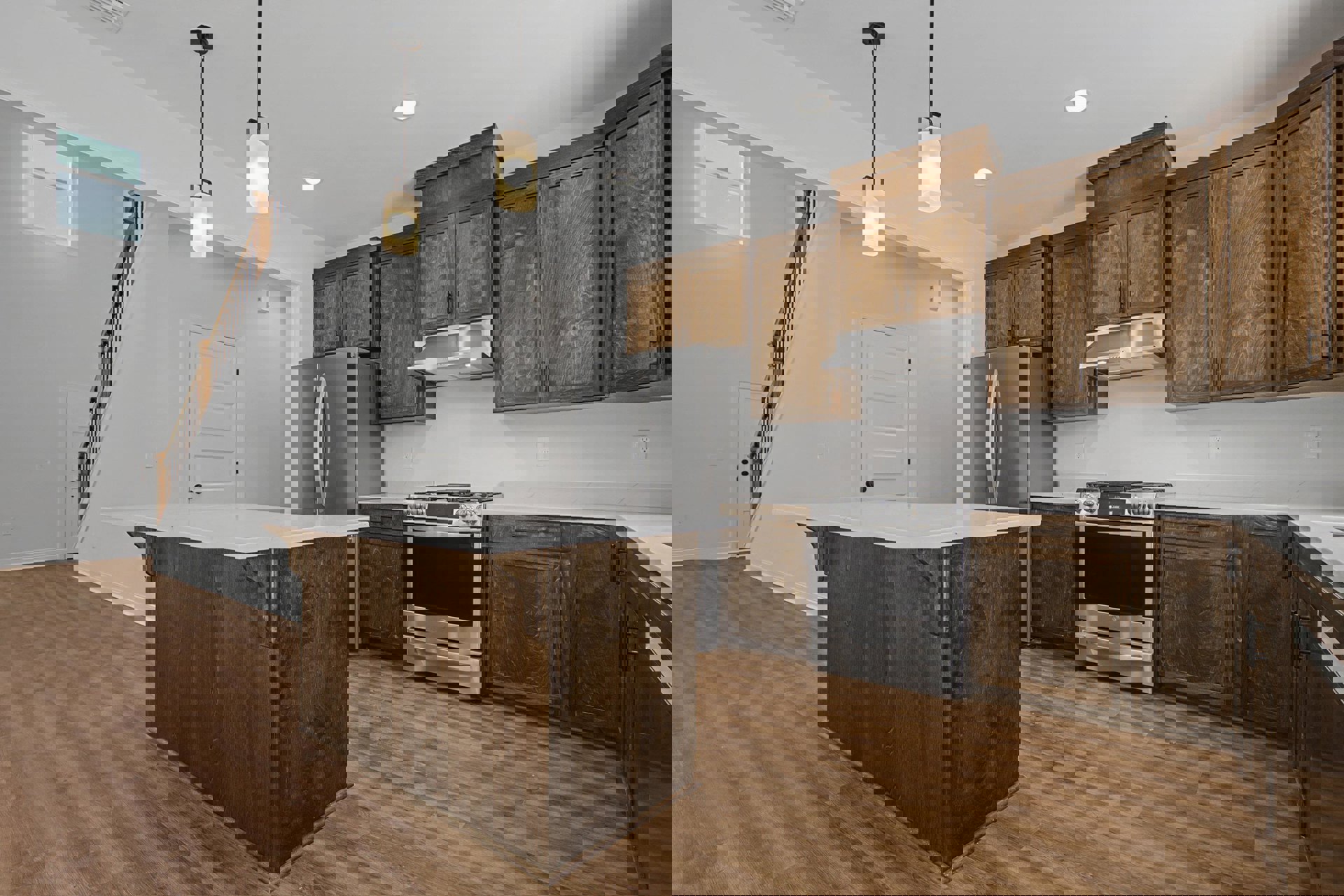 Kitchen with natural wood cabinets, stainless steel refrigerator and stove, white countertops, wall-mounted light fixture, and light wood flooring.