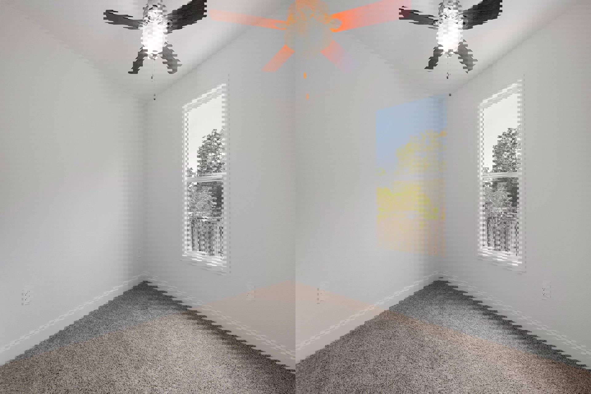 Ceiling fan with light fixture mounted on white plaster ceiling above carpeted floor, window revealing trees and parked car in driveway