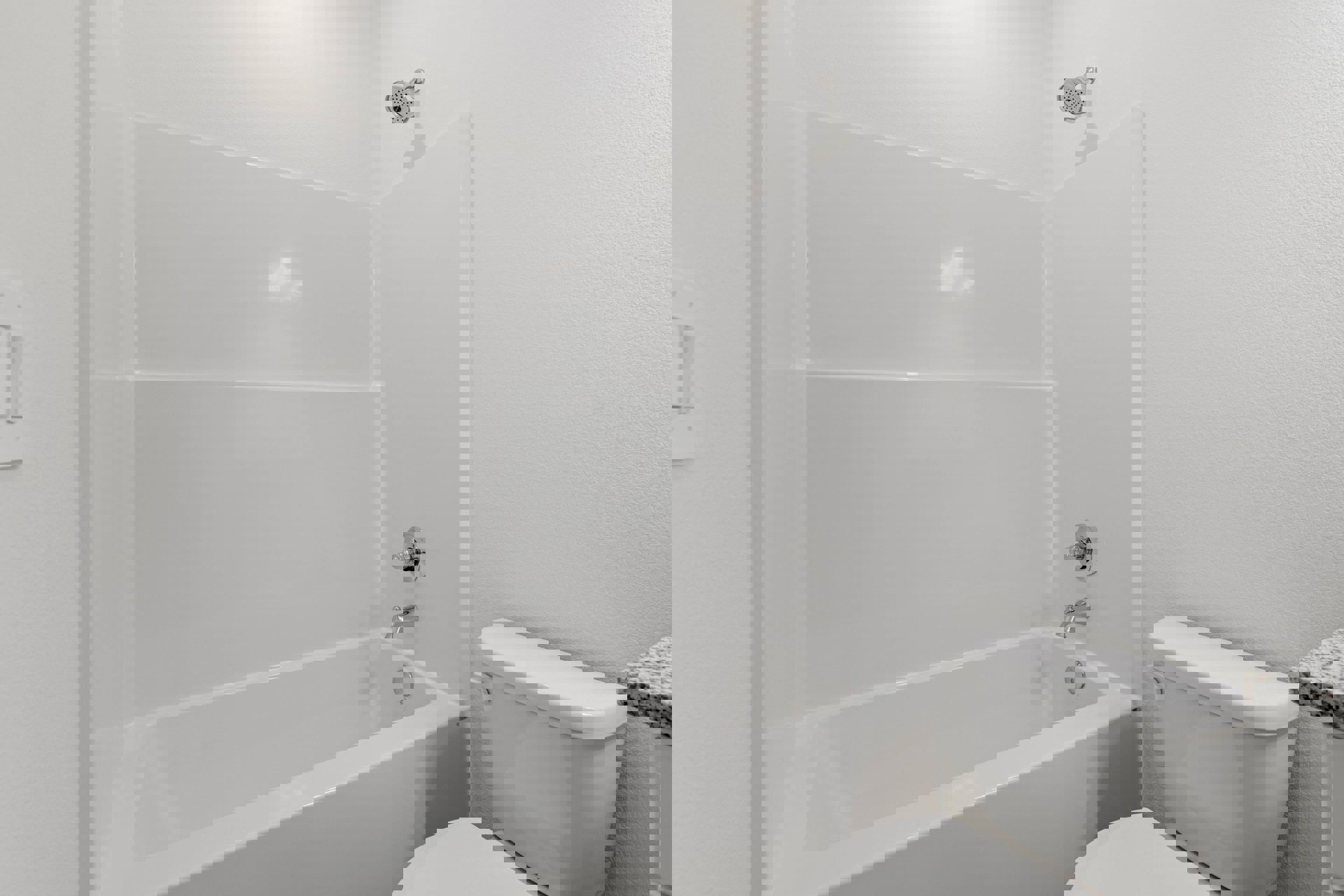 White tile bathroom featuring a freestanding bathtub, modern faucet, round shower head, and adjacent toilet.