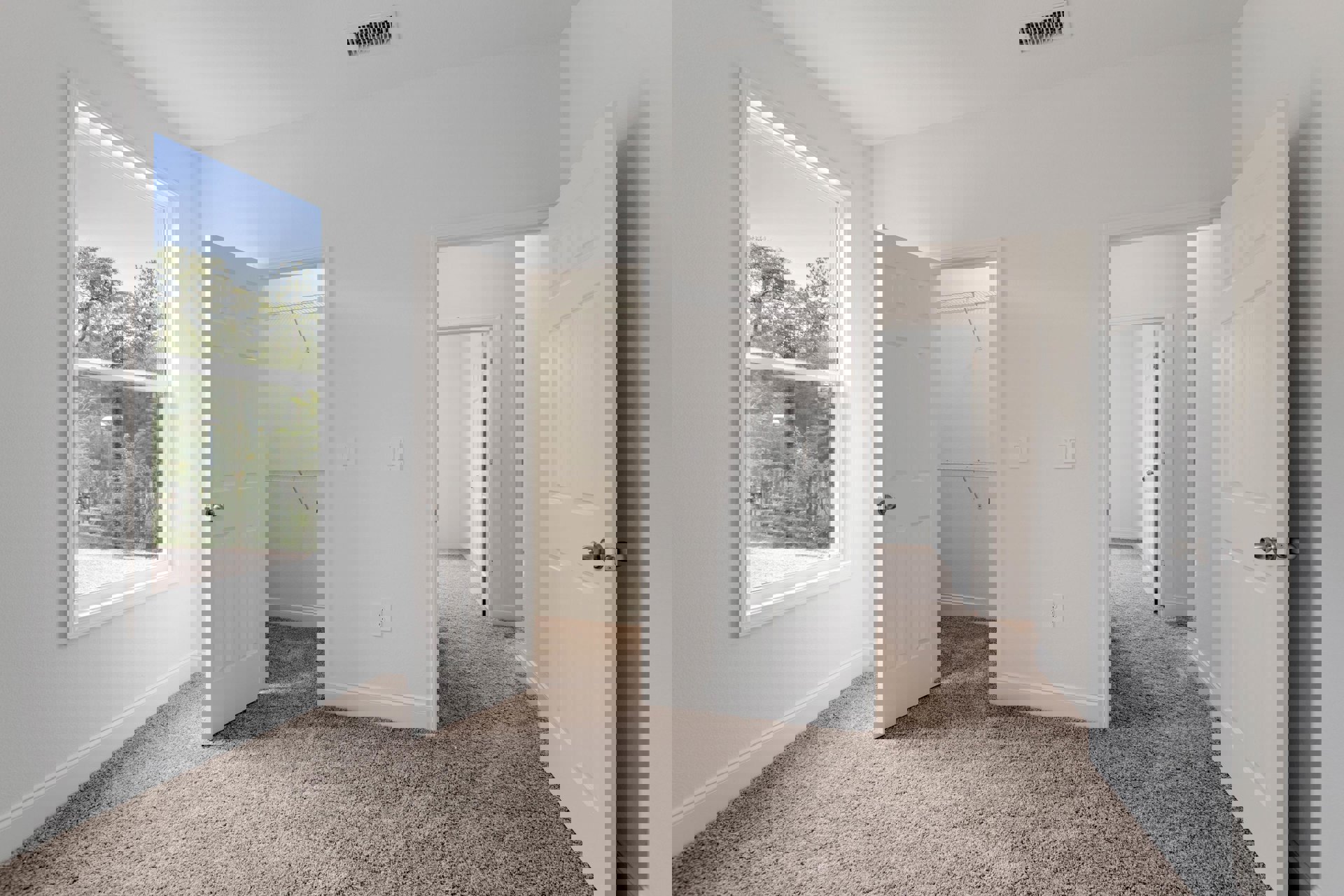 Carpeted room with white walls, open white doors with silver knobs, ceiling vent, and window overlooking trees