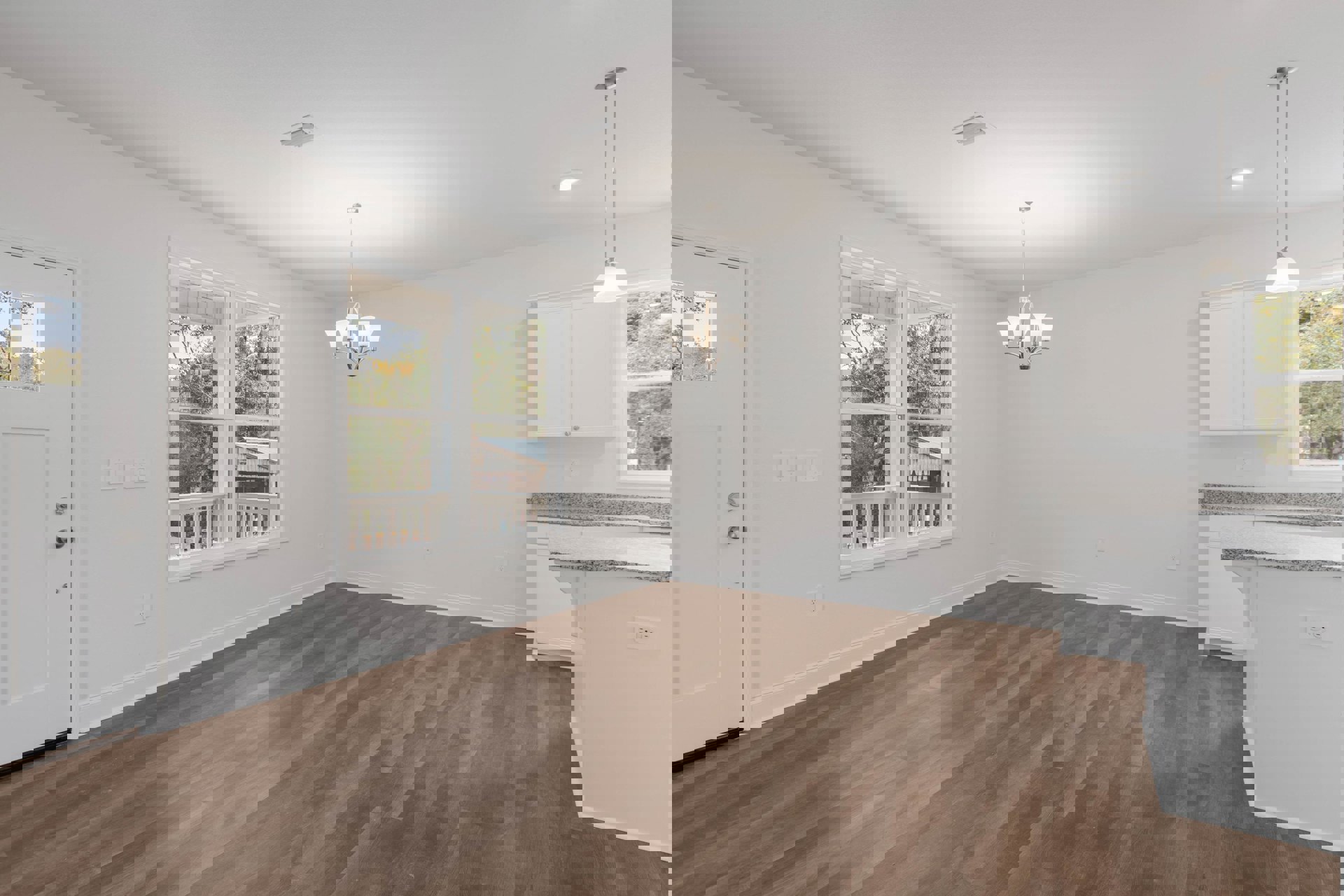 Hardwood flooring and white walls in a bright room, window overlooking porch and trees, chandelier with white shades, close-up of white door, silver pole against white background