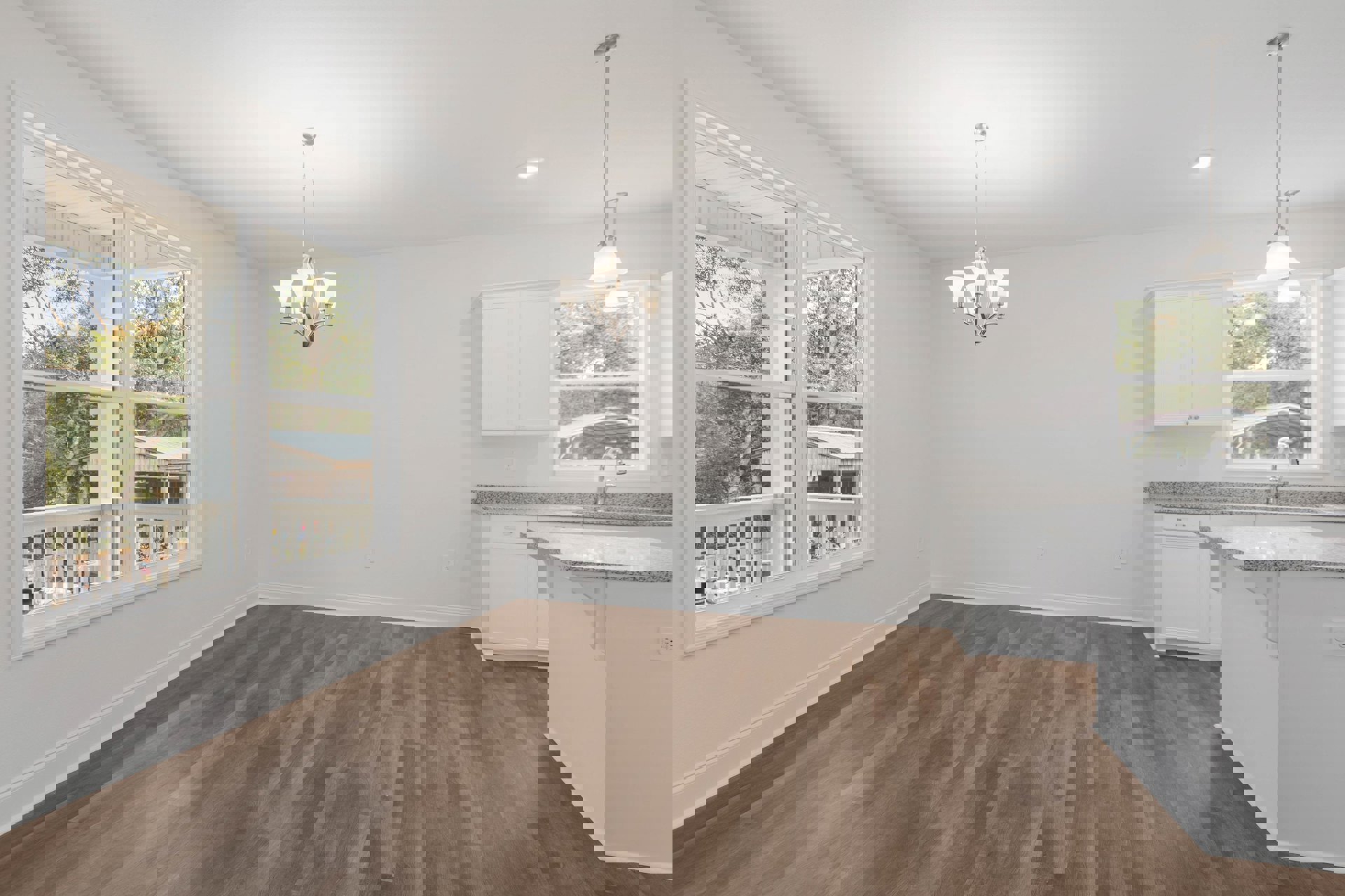 Open kitchen with white cabinetry and island, wood laminate flooring, white walls, stainless steel sink and faucet