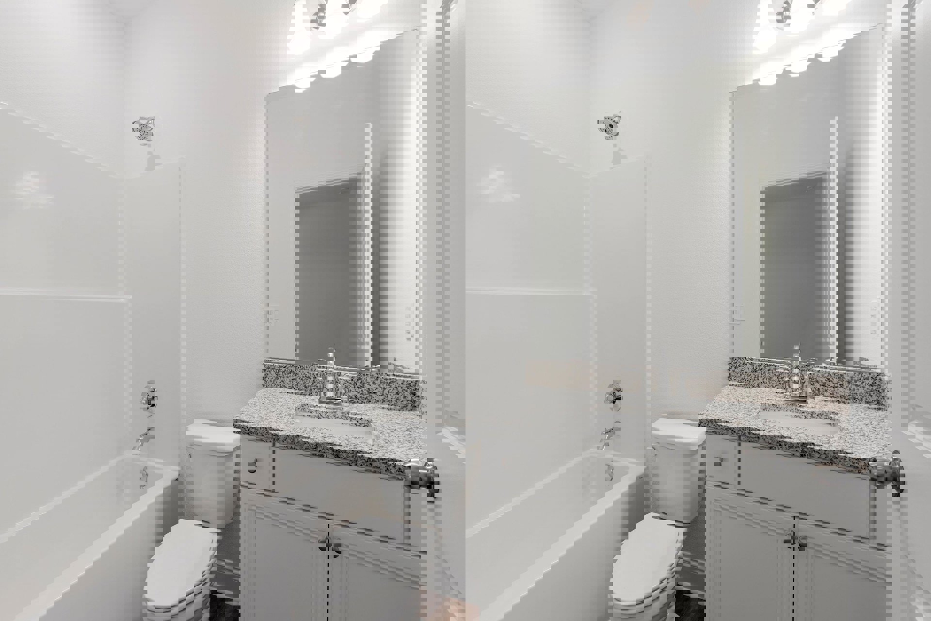 Bathroom with white tile walls, white bathtub, round shower head, white toilet with closed lid and chrome handle, single sink with chrome faucet