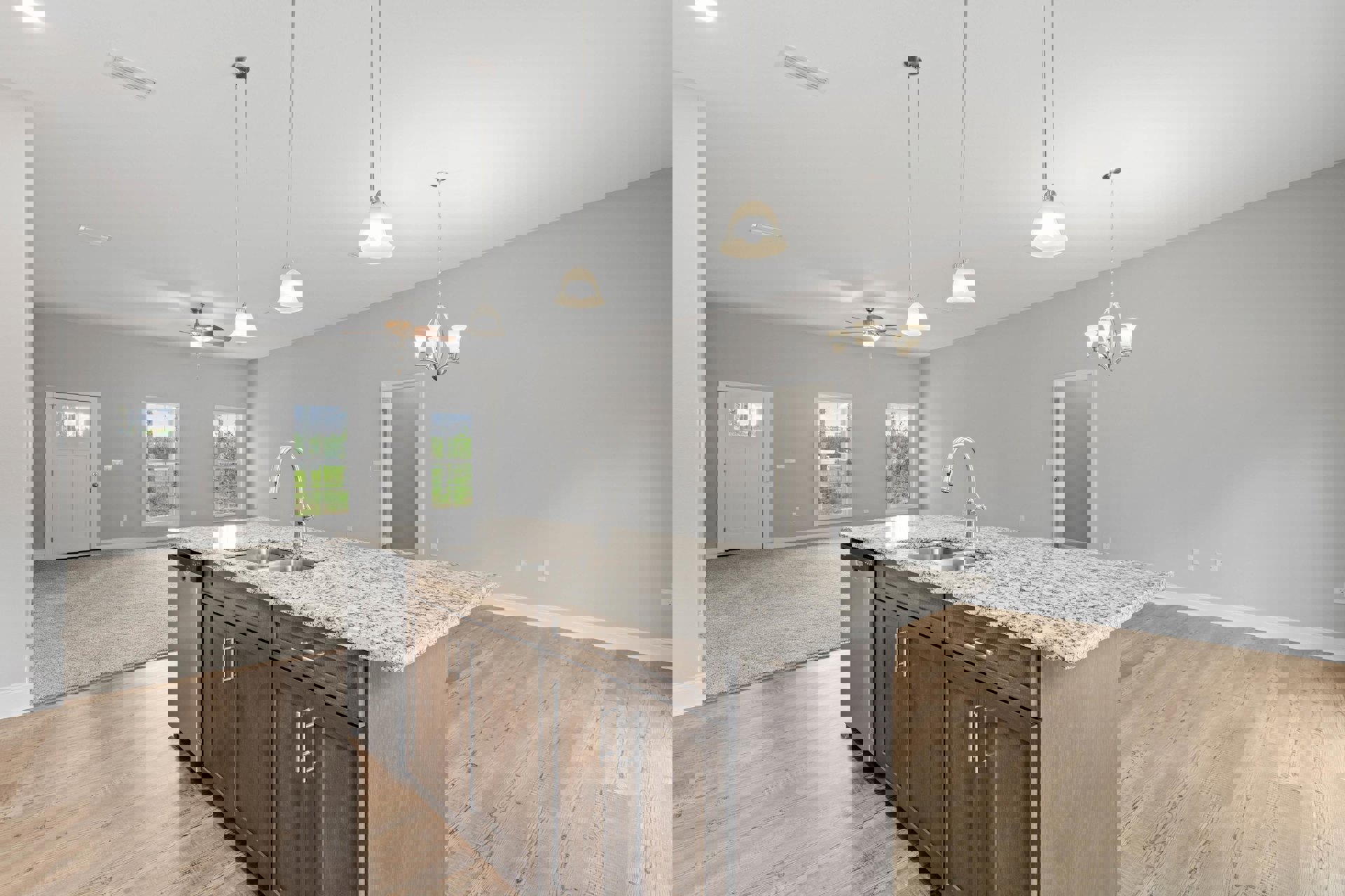 Kitchen featuring a large granite island with built-in sink, white cabinetry, tile flooring, and a window overlooking trees.
