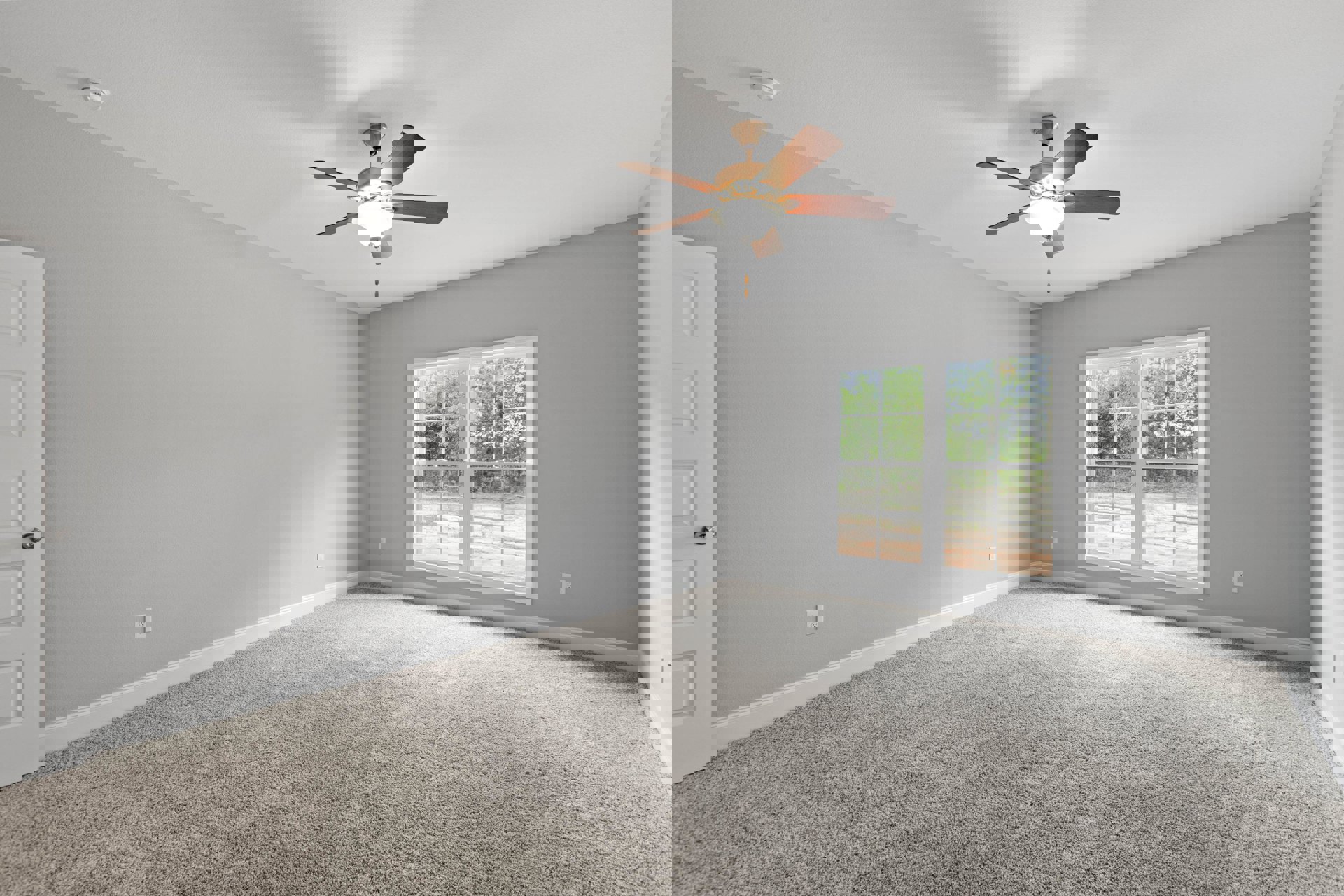 Carpeted room with white ceiling, ceiling fan and light fixture, window showing green trees, close-up of brass door knob, neutral walls with crown molding