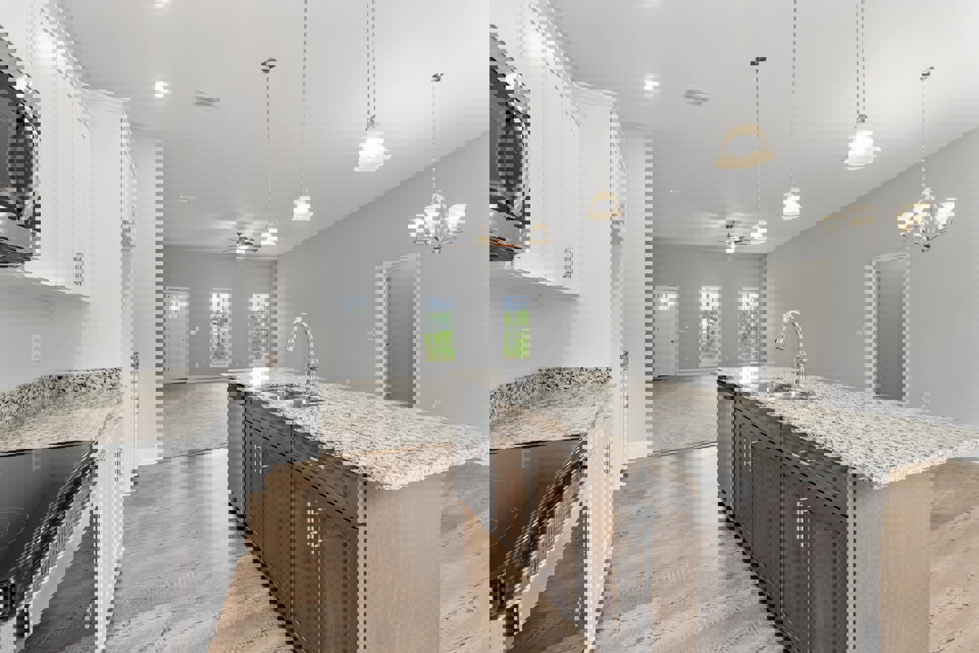 Granite countertops and kitchen island with built-in sink, stainless steel microwave and stove, white cabinetry, window with tree view, white door with glass panel