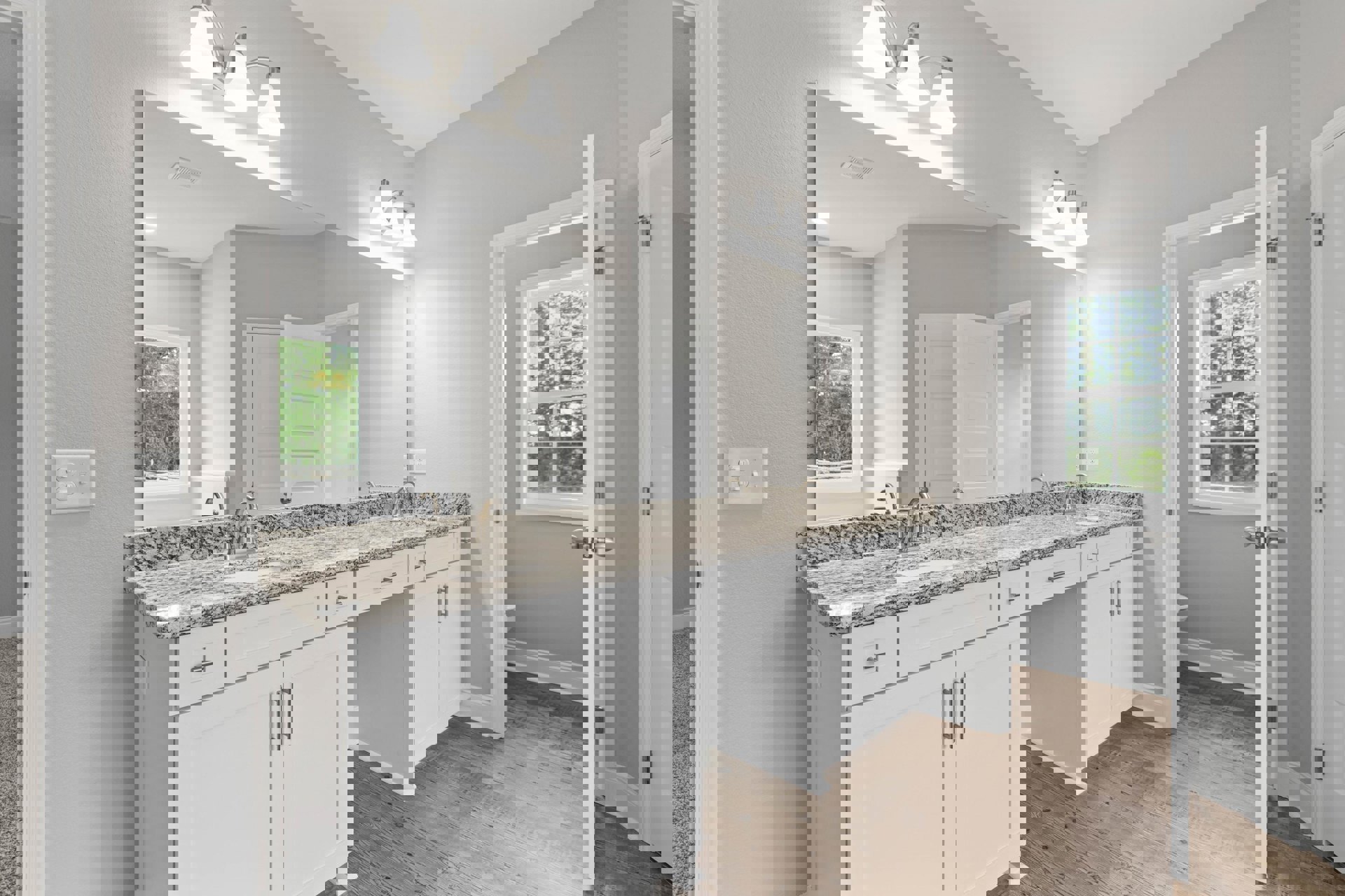 Bathroom with marble countertop, white cabinetry, multi-pane window overlooking trees, chrome faucet, white light switch, modern light fixture, white door, tiled floor