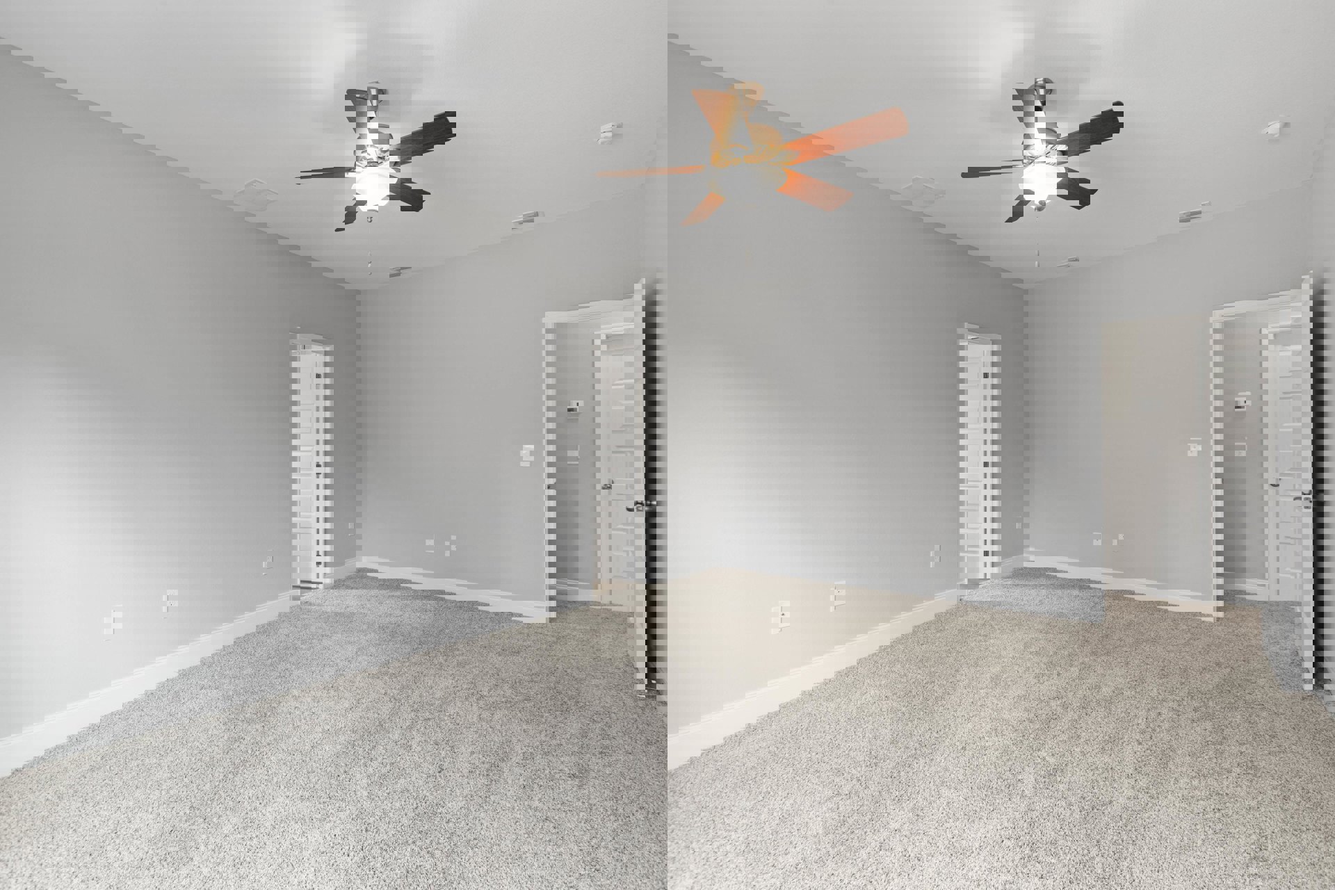 Carpeted room with white walls, ceiling fan and light fixture, open white door, visible thermostat and light switch near doorway