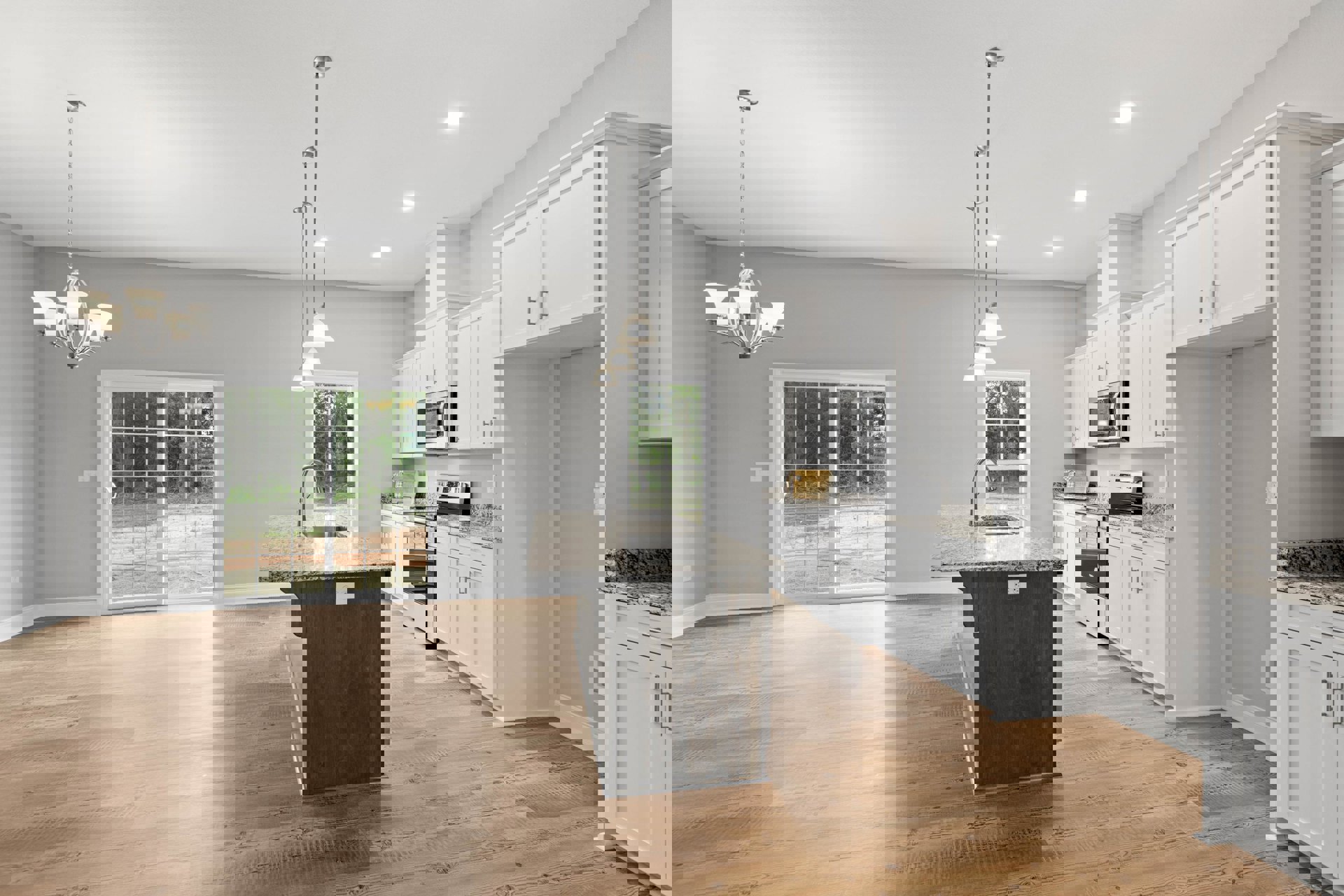 Spacious kitchen featuring a large marble-topped island, white shaker cabinets, stainless steel microwave, pendant lighting, wide window with outdoor view, and white walls with